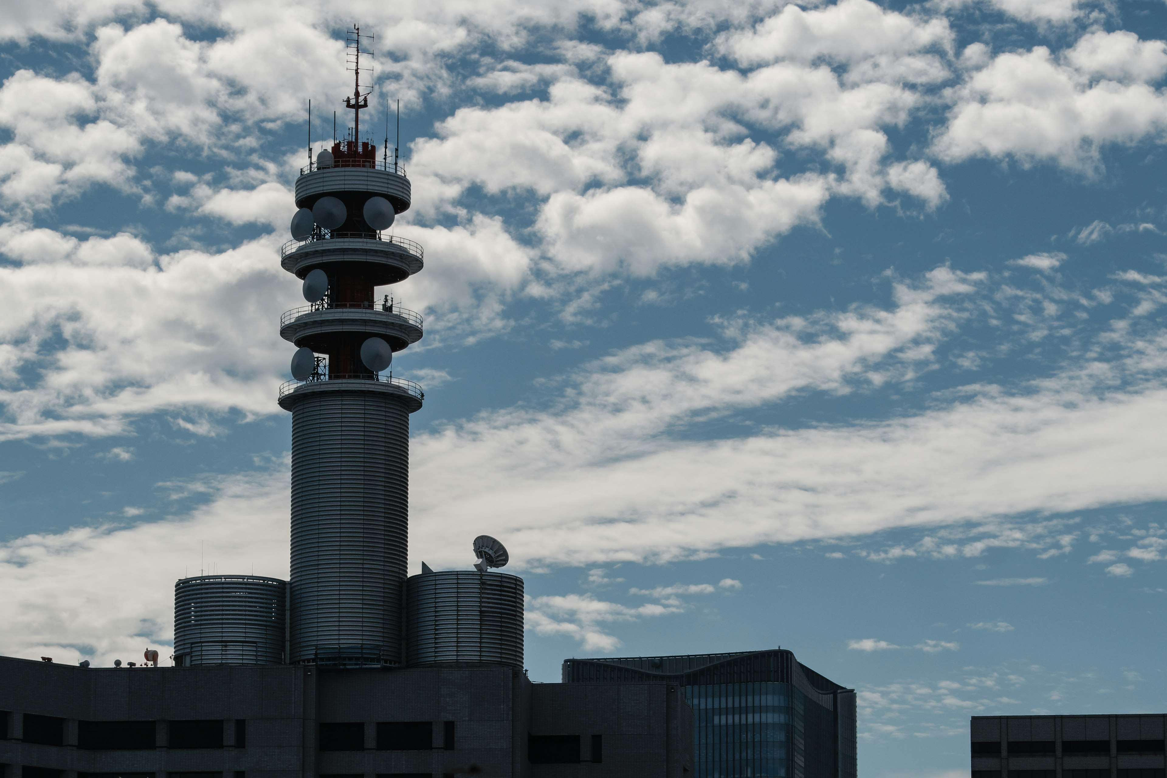 Tour de communication en silhouette contre un ciel bleu avec des nuages