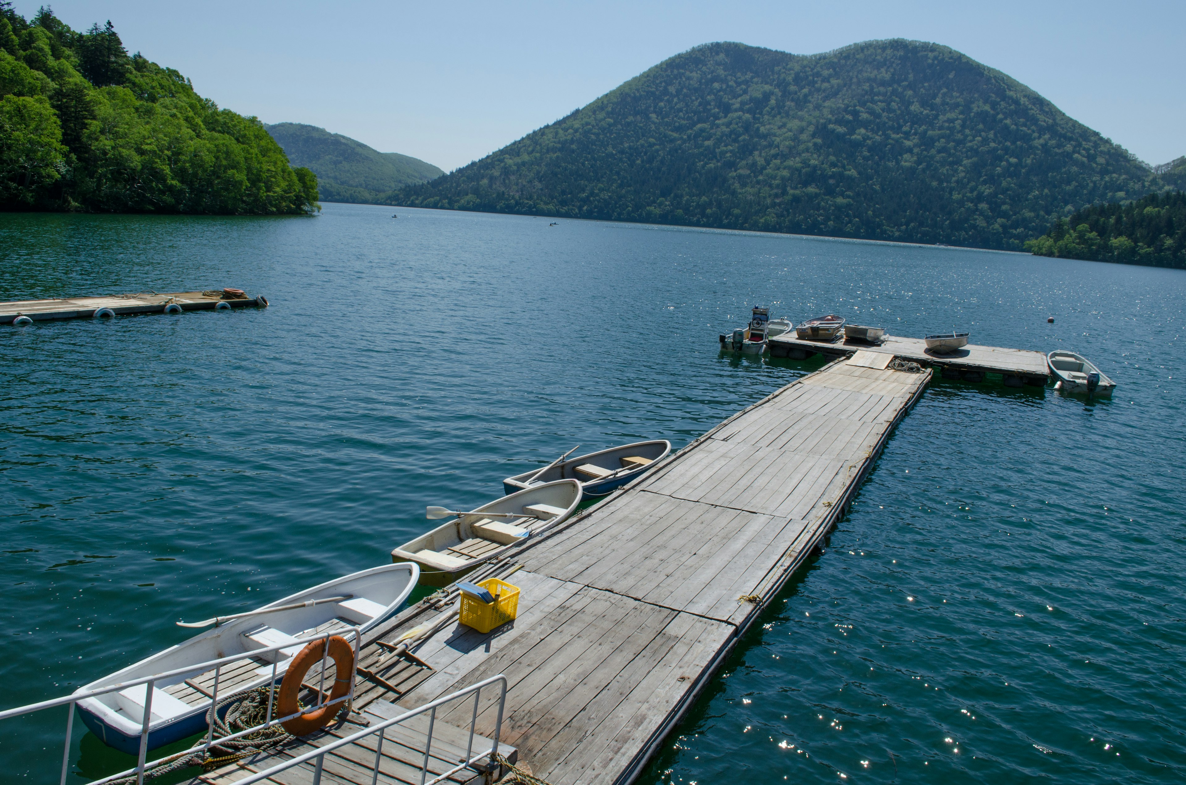 Scenic view of a dock with boats on a lake surrounded by green mountains