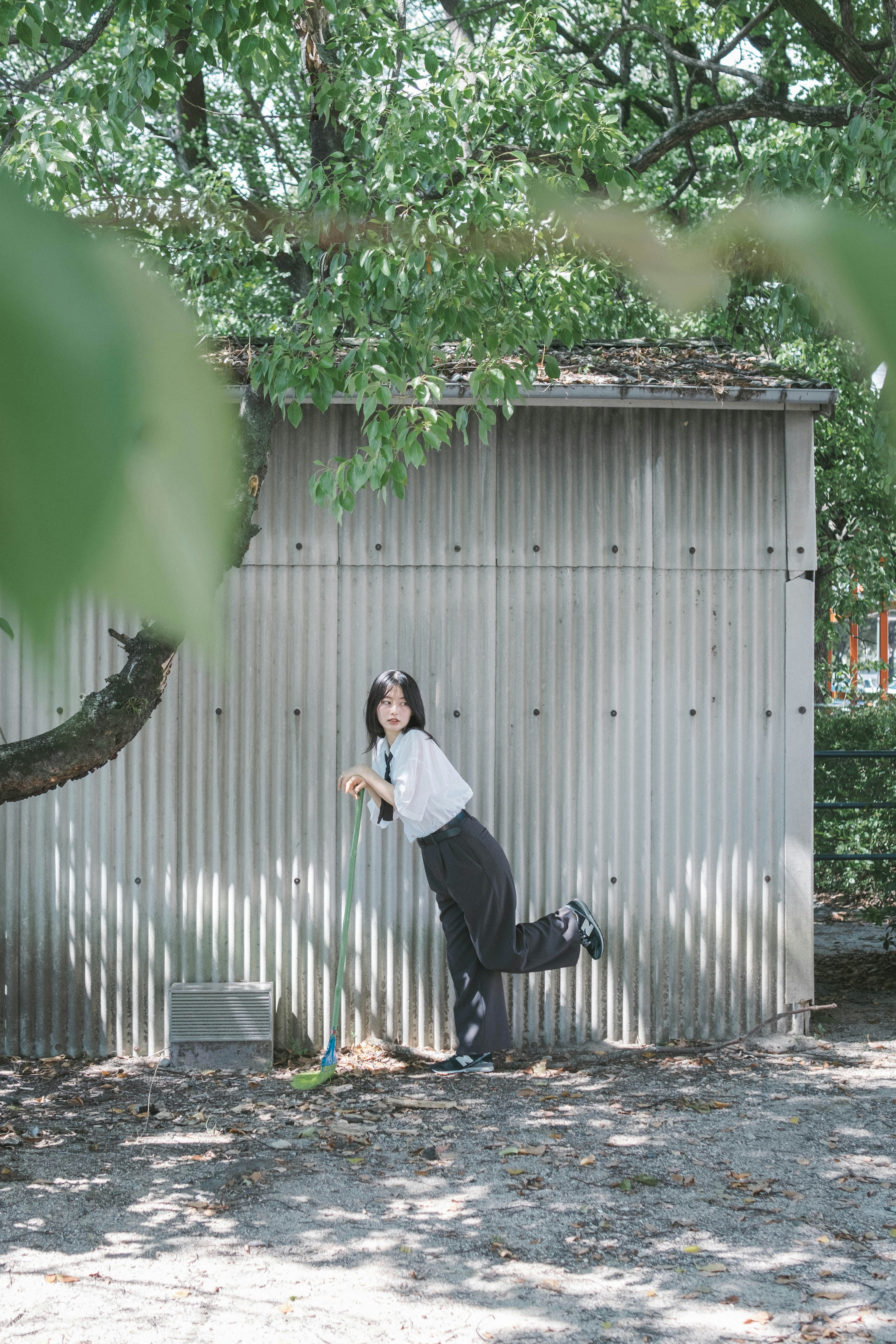 Une femme posant sous un arbre devant un fond simple