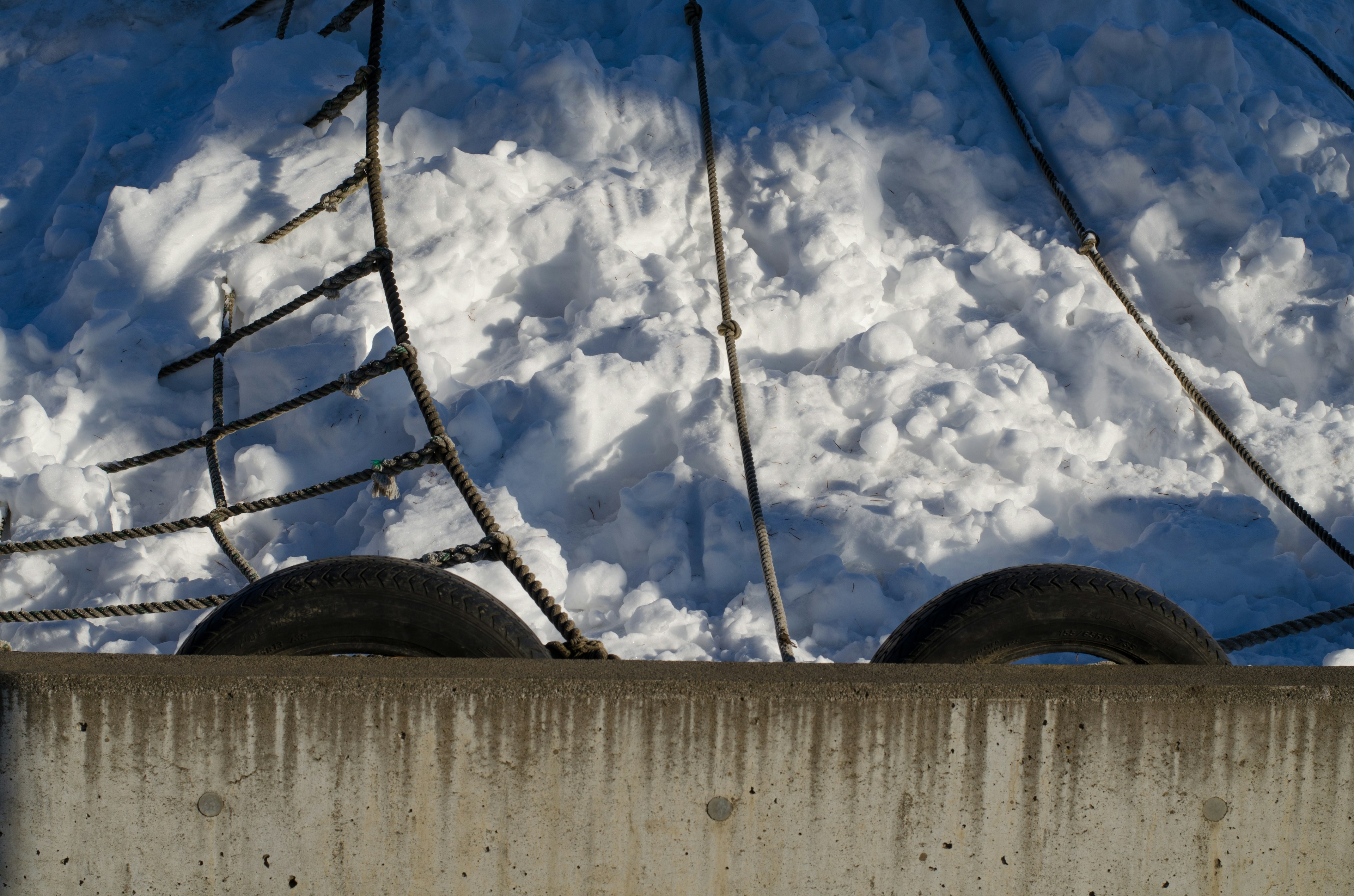 A concrete wall with black tires and a backdrop of snow