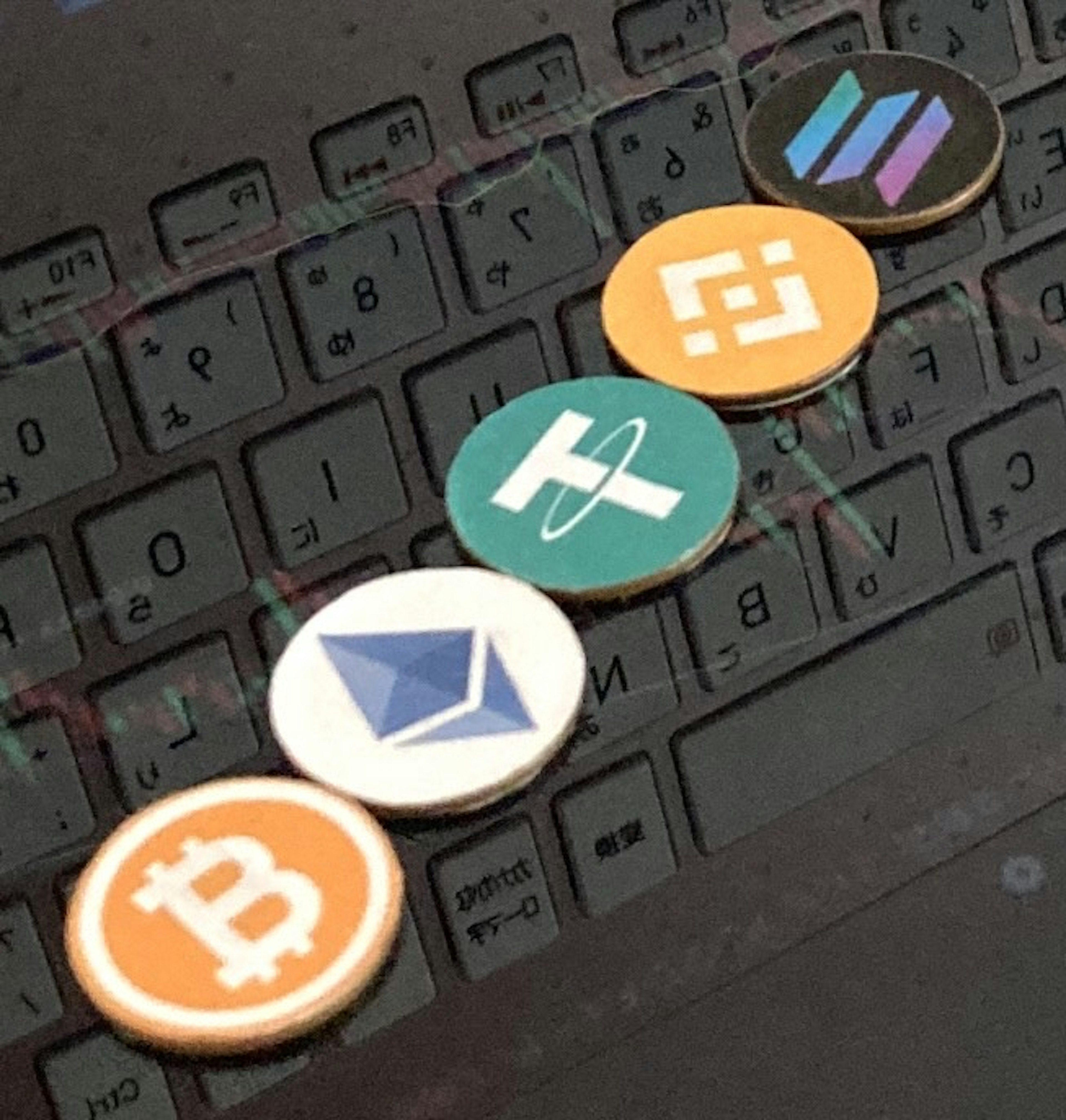 Posavasos con logotipos de criptomonedas dispuestos sobre un teclado