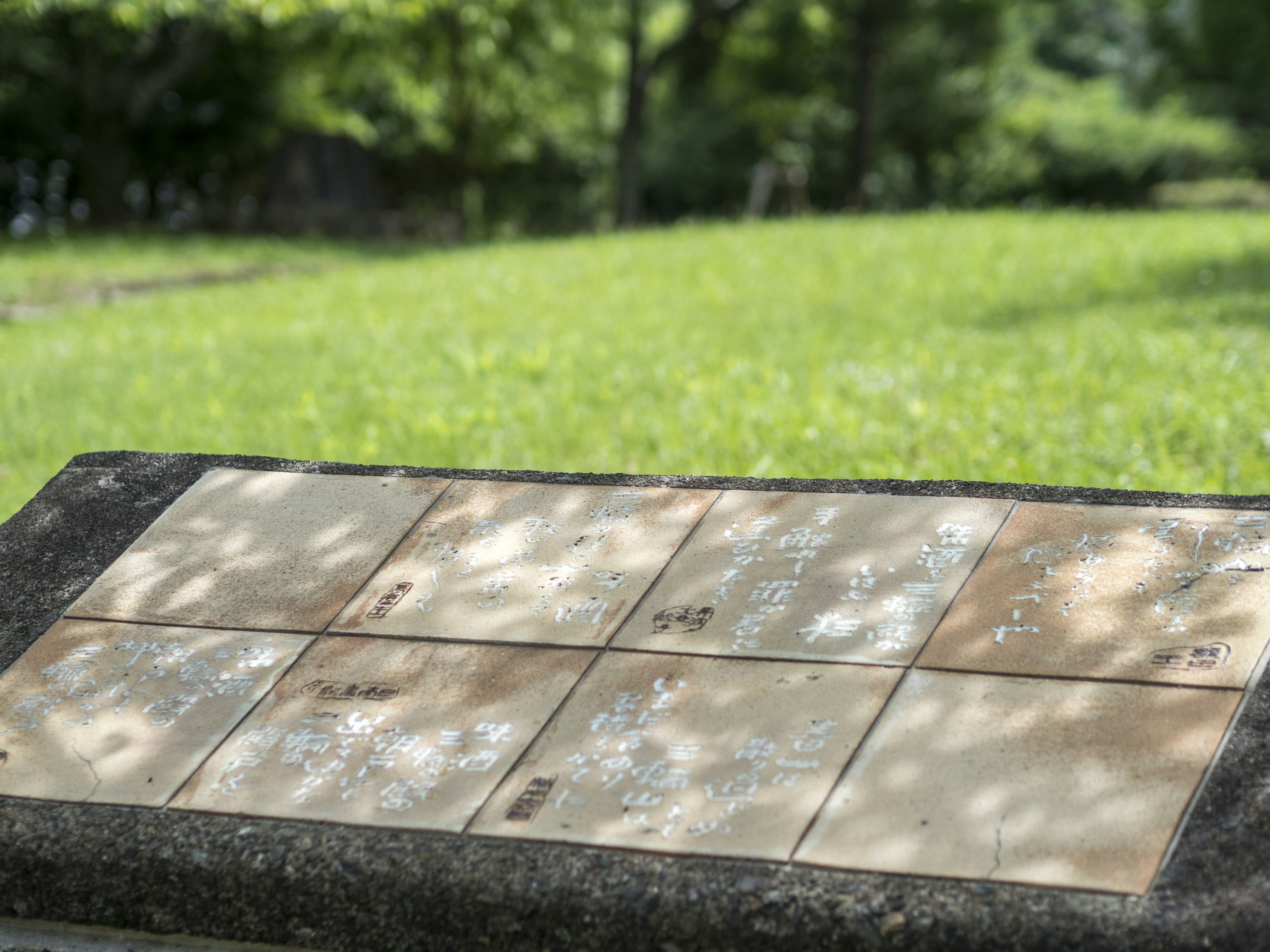 Steintafel mit eingraviertem Text vor grünem Hintergrund