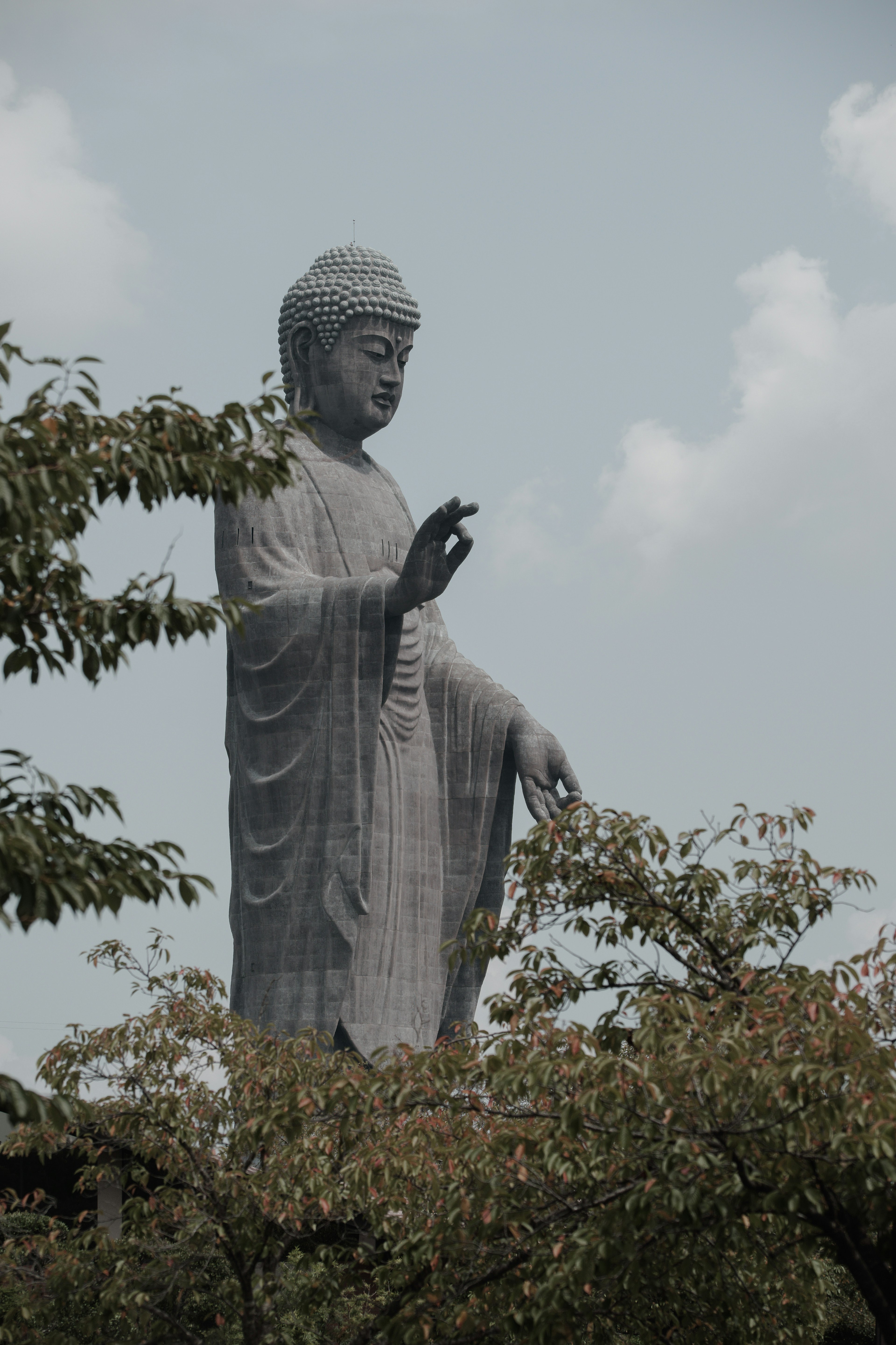 Patung Buddha tinggi dikelilingi pepohonan dalam pemandangan tenang