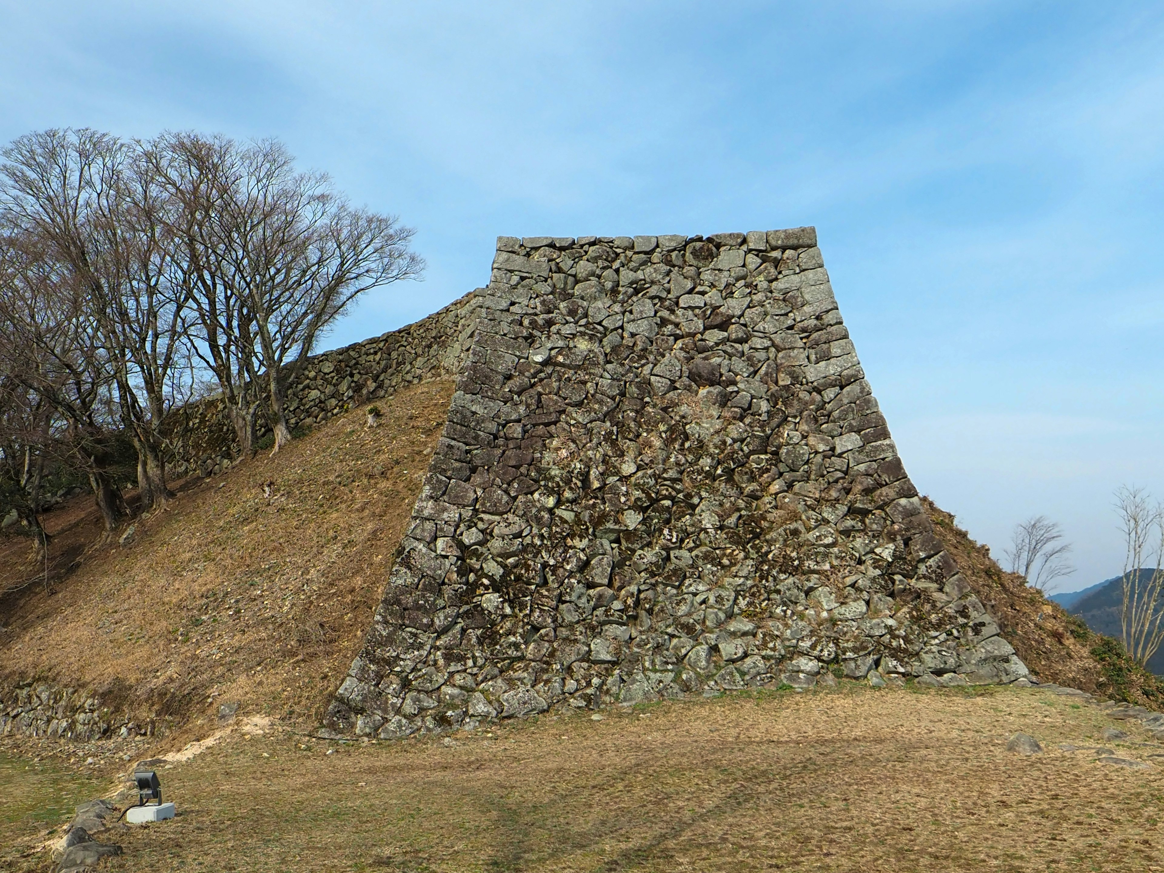 石でできた古代の城壁の一部が青空の下に立っている