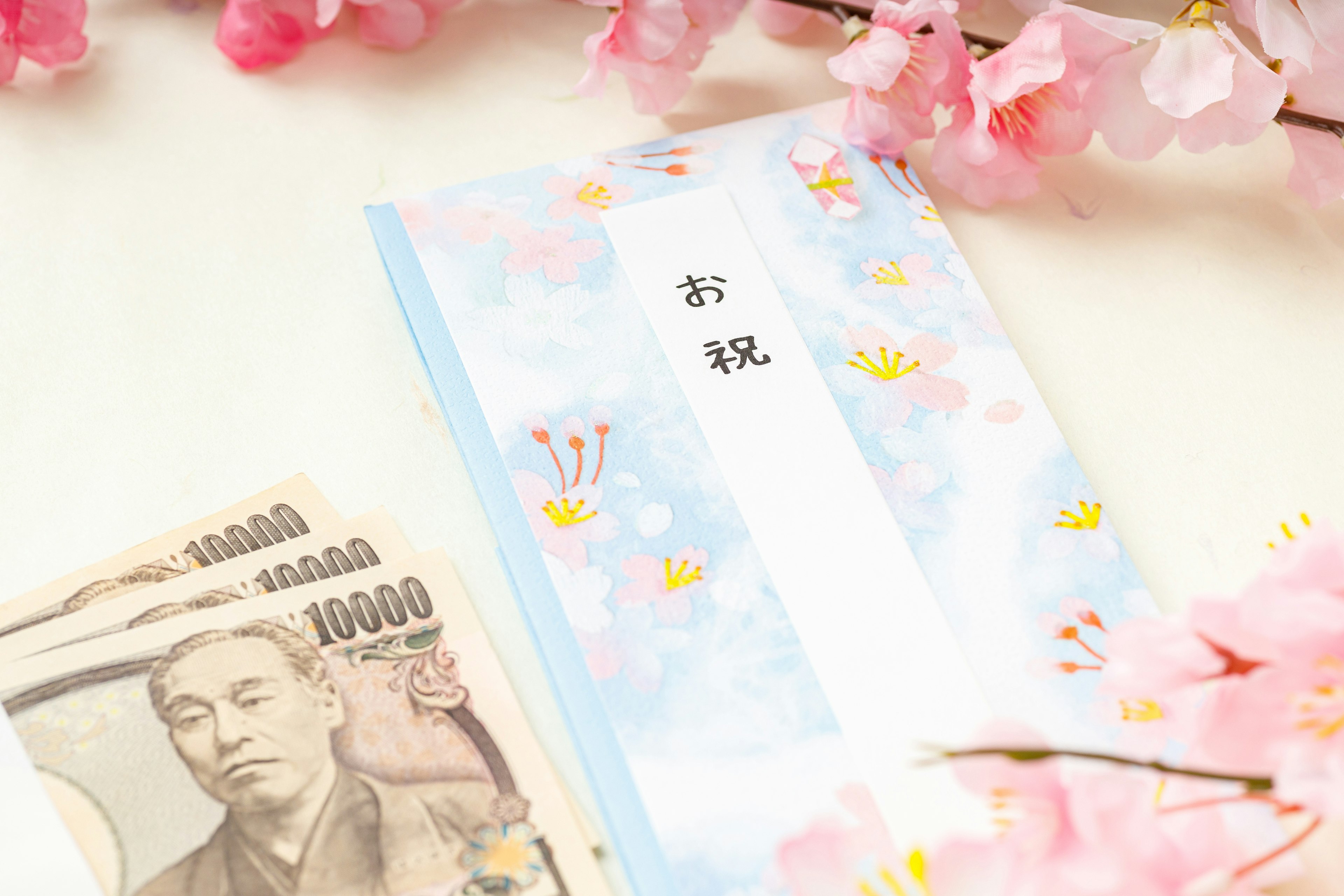 Japanese celebration envelope with a ten thousand yen note surrounded by cherry blossoms