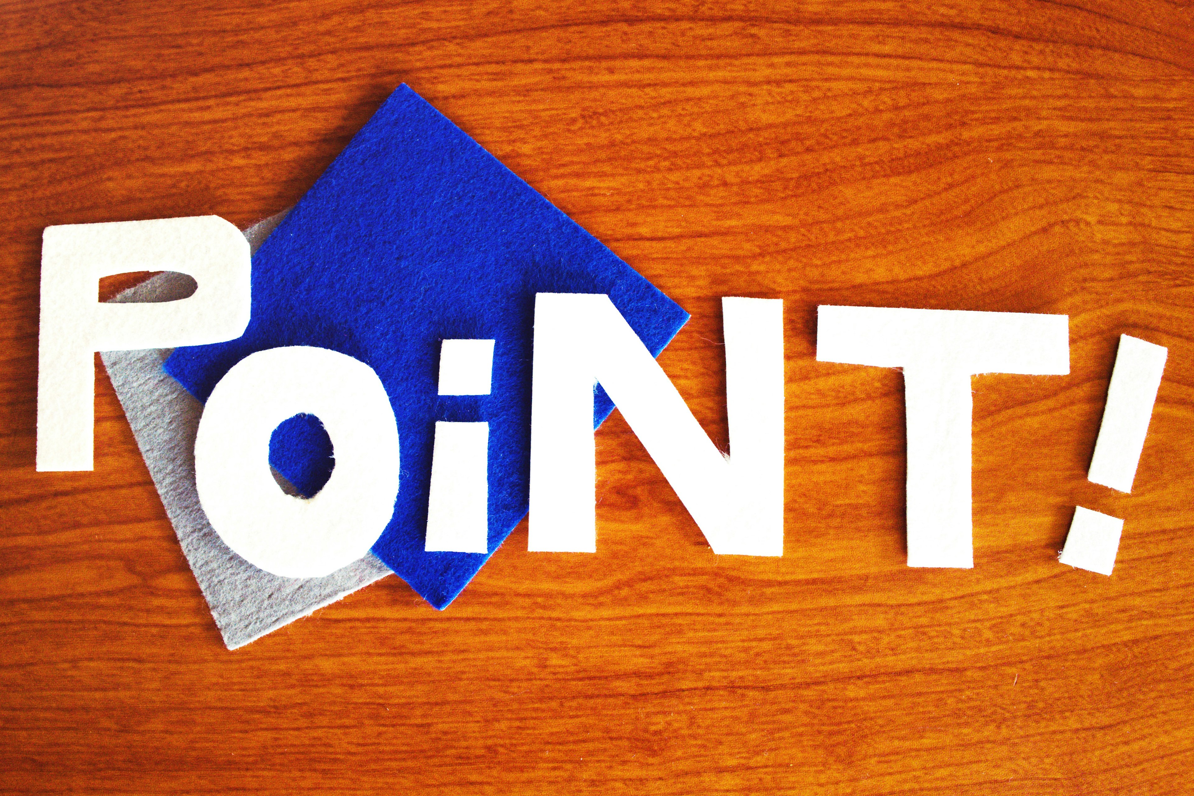 Image featuring the word 'POINT' in white letters on a wooden surface with blue and gray fabric squares