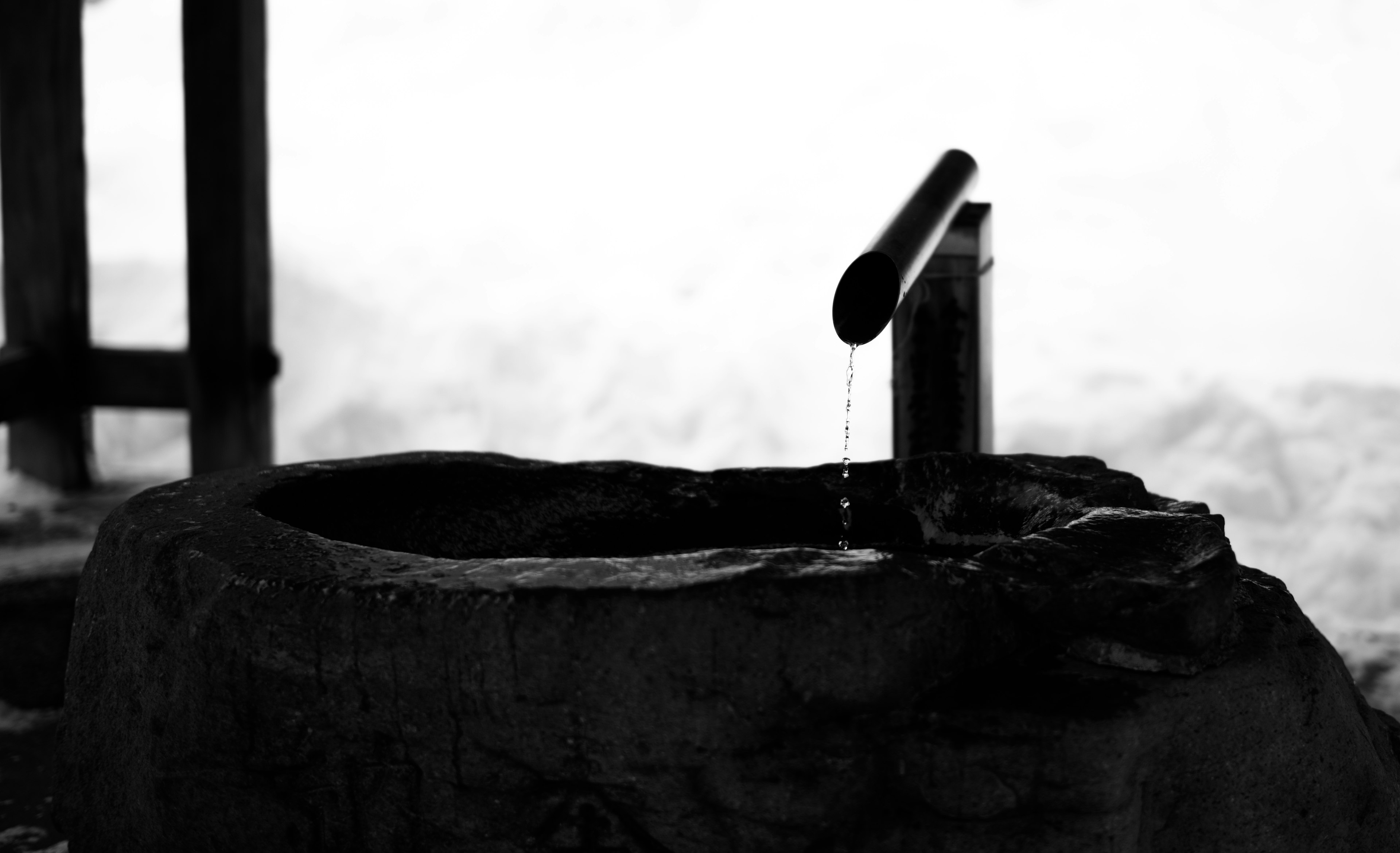 Silhouette eines alten Brunnens mit fließendem Wasser und verschwommenem Hintergrund