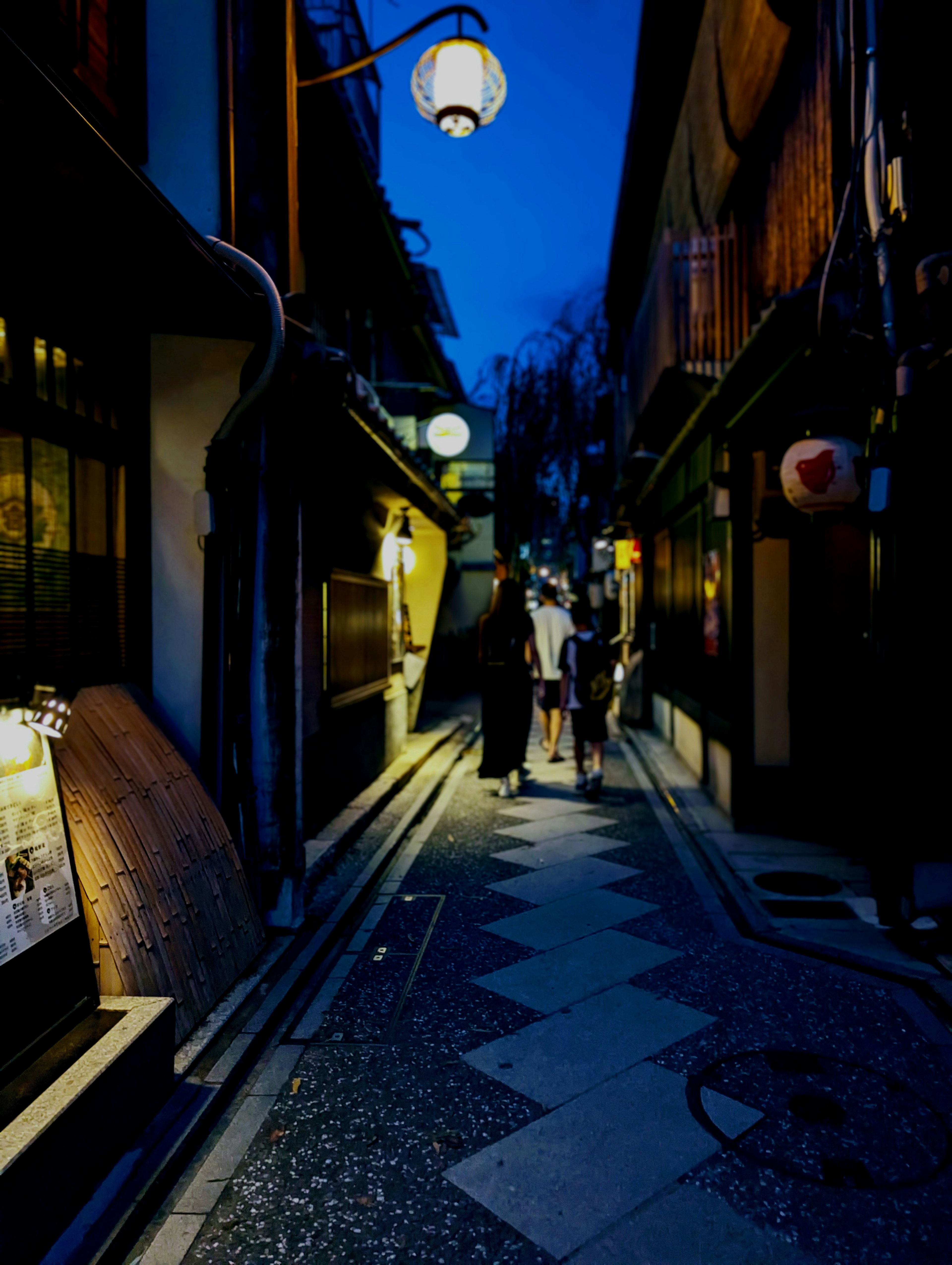 Callejón tenuemente iluminado con personas y faroles