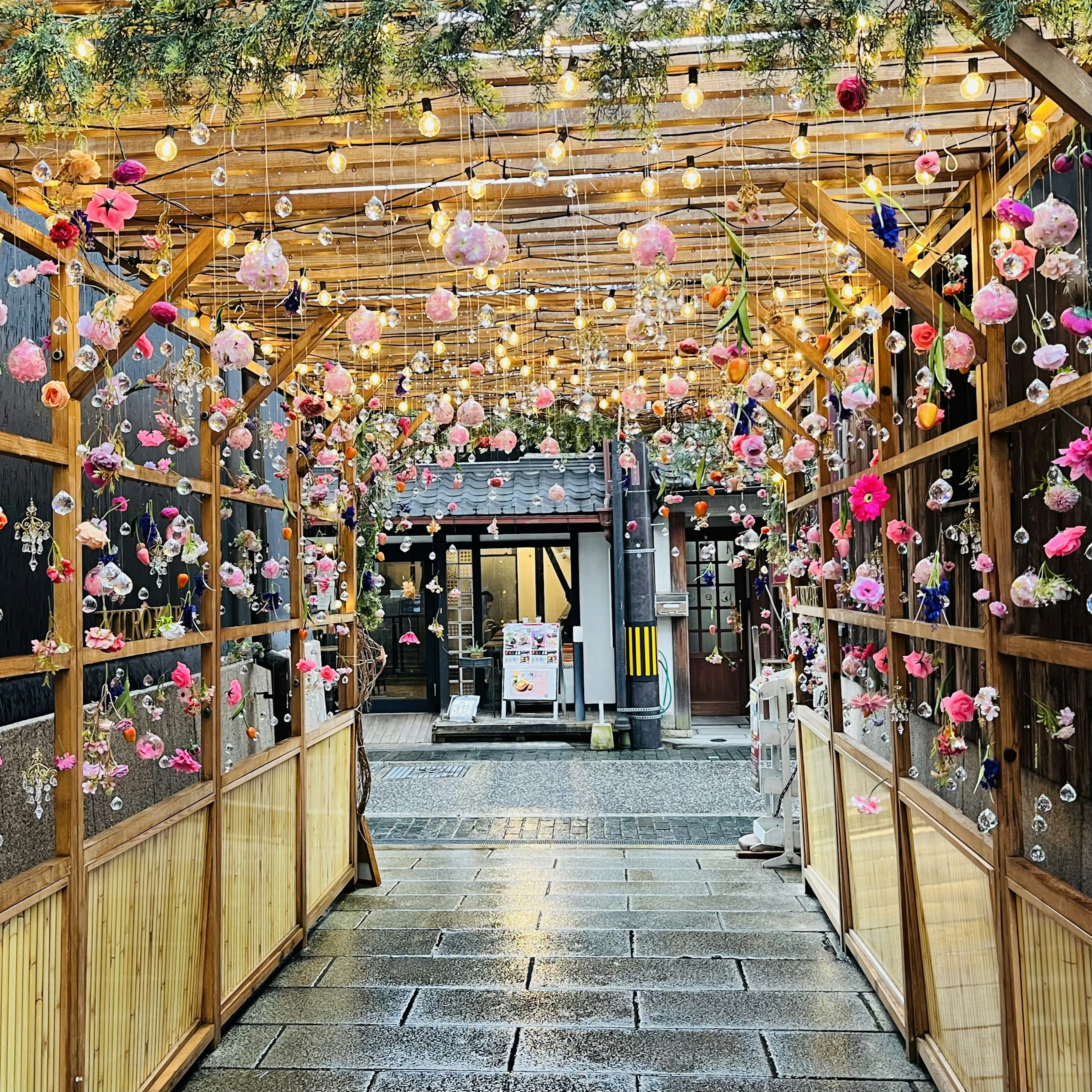 Bellissimo passaggio adornato di fiori e luci in un'arcata di legno