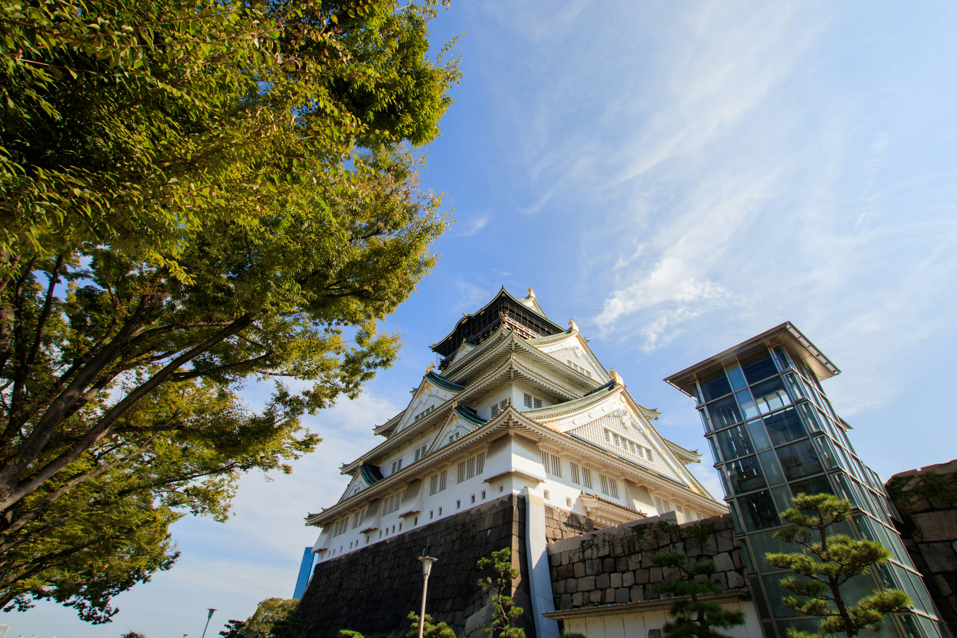 Japanese castle towering under a blue sky alongside a modern building