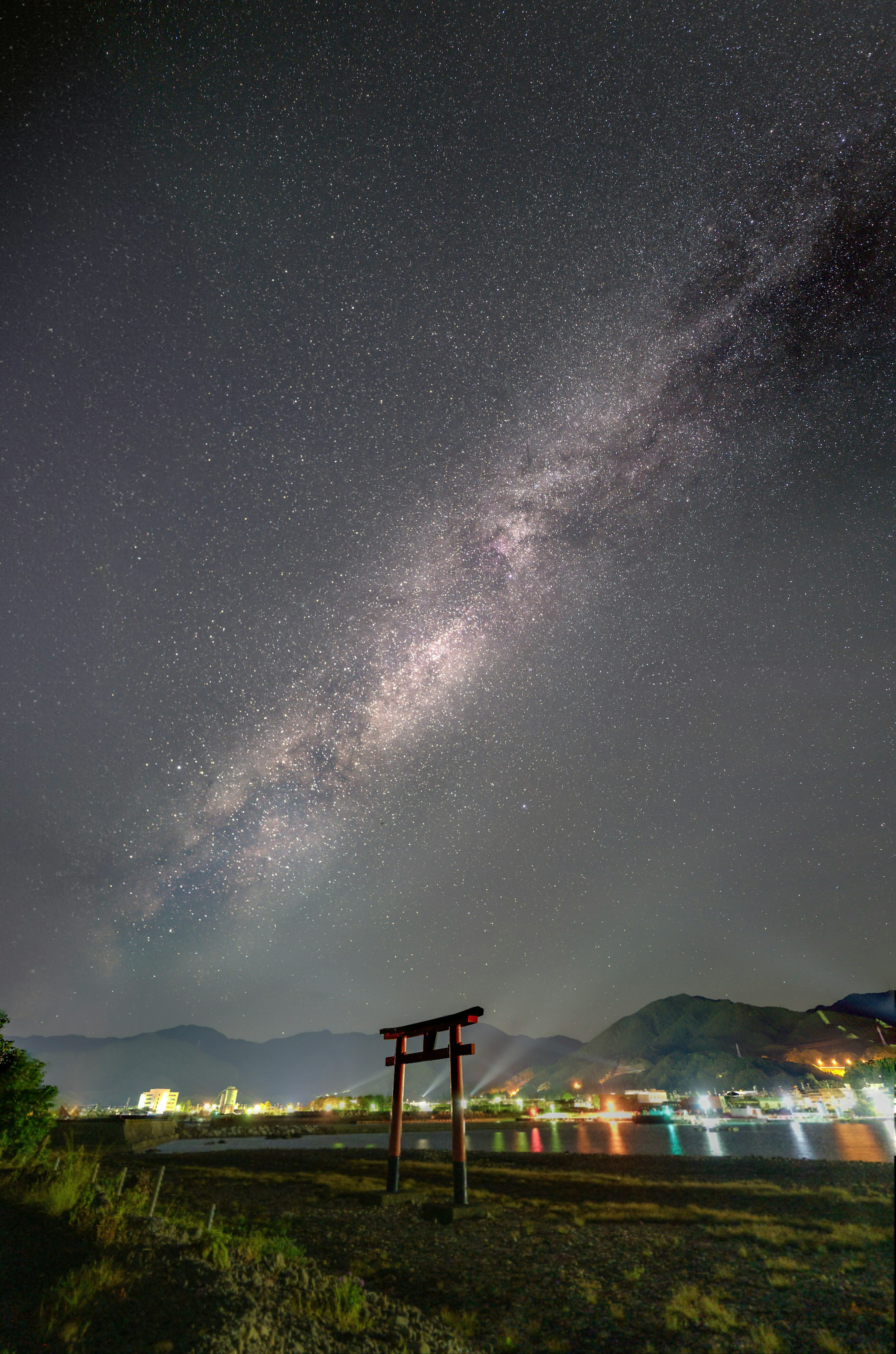 Pemandangan malam yang indah dengan langit berbintang dan pantulan di air Torii di latar depan