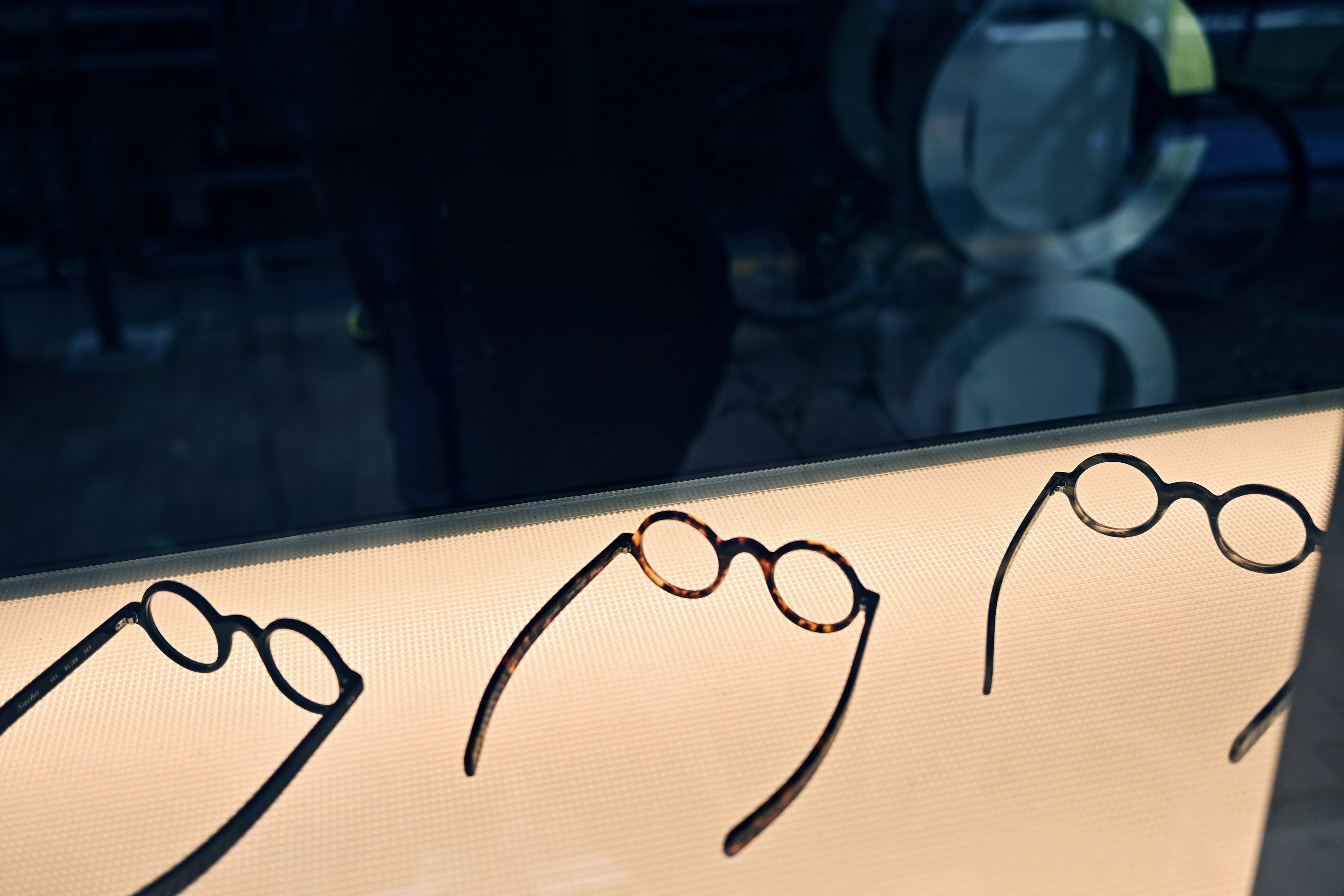 Three pairs of black-framed glasses displayed on a counter