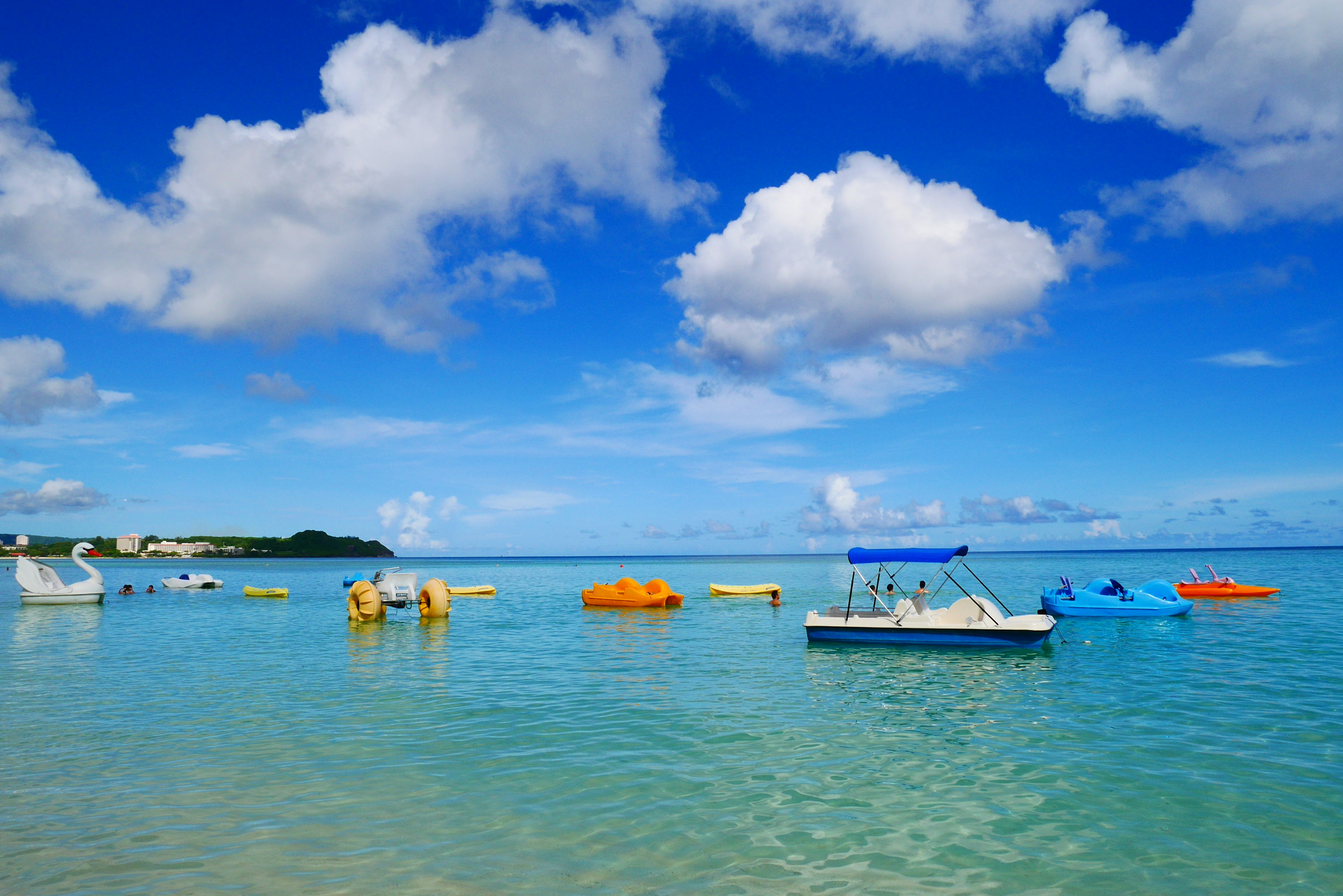 Colorful boats floating on a clear water surface under a blue sky