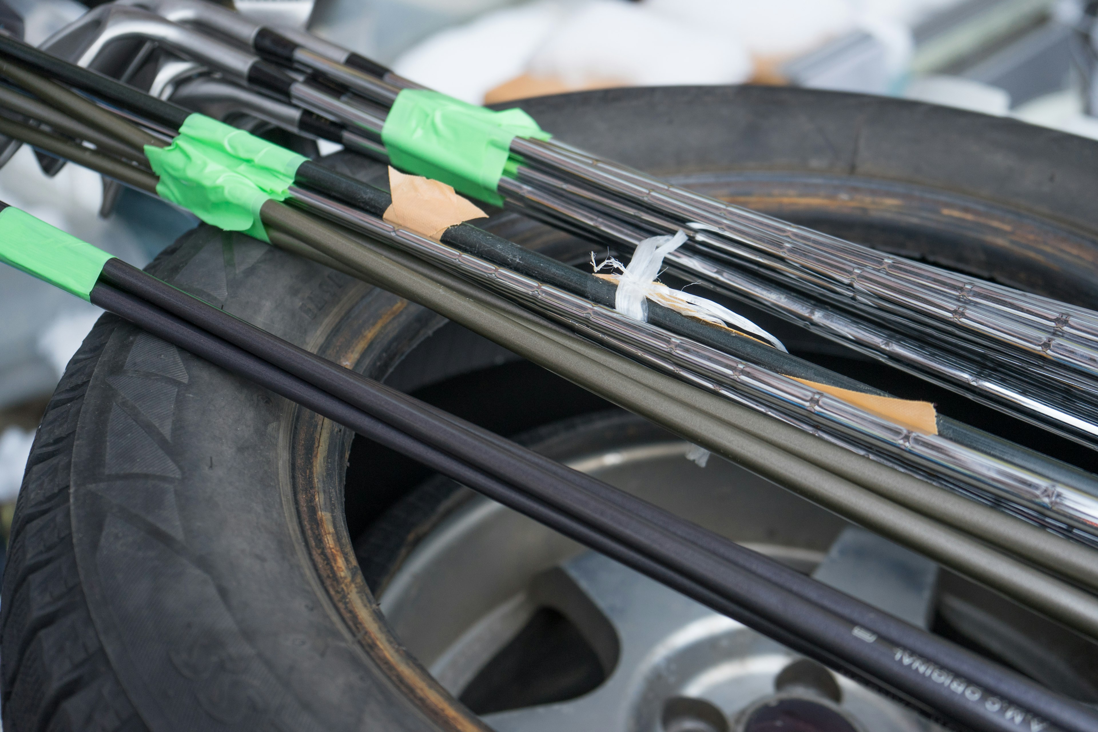 Fishing rods secured with green tape resting on a tire