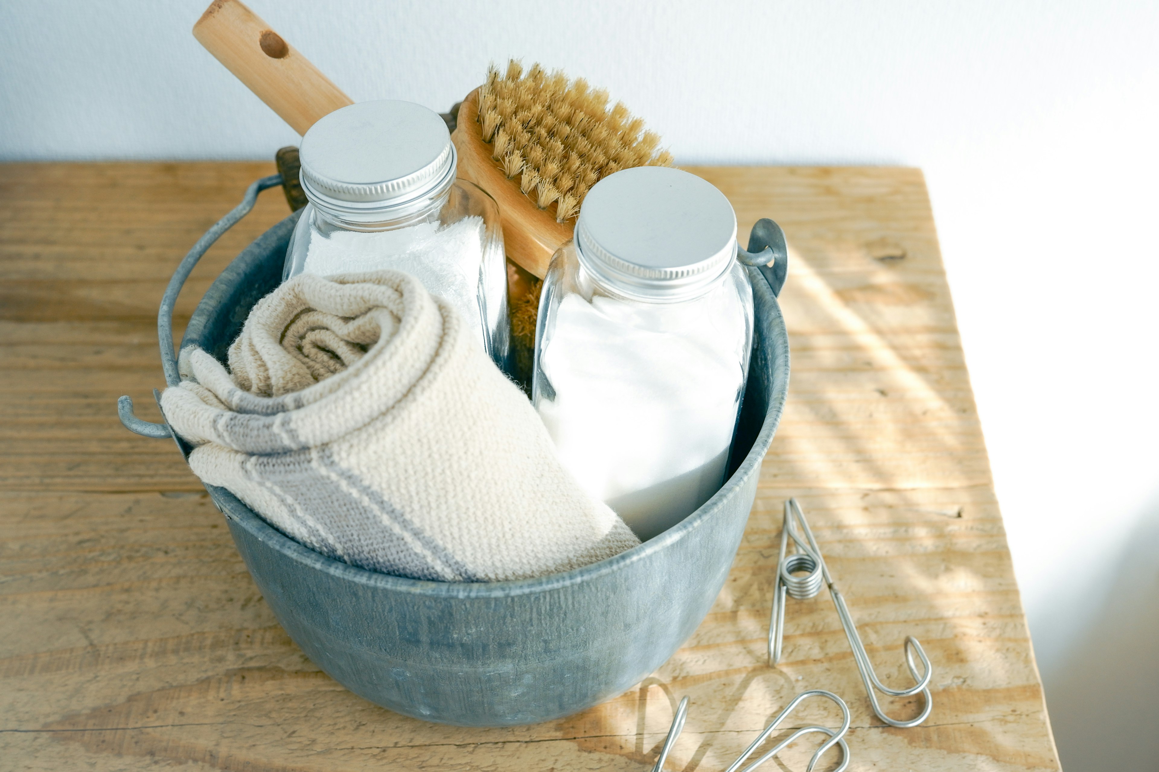 A blue bucket containing towels and brushes on a wooden surface