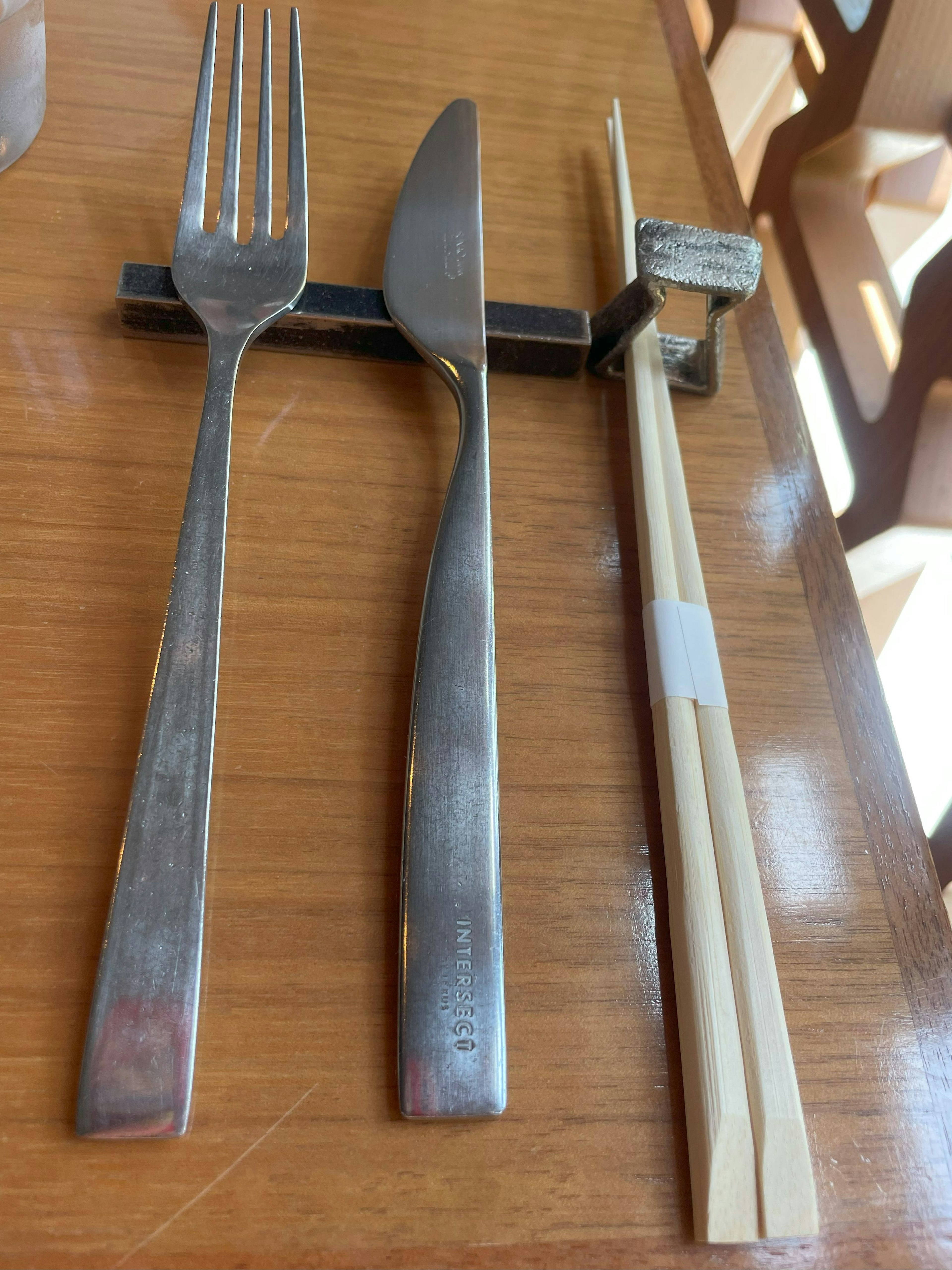 Fourchette couteau et baguettes disposés sur une table en bois