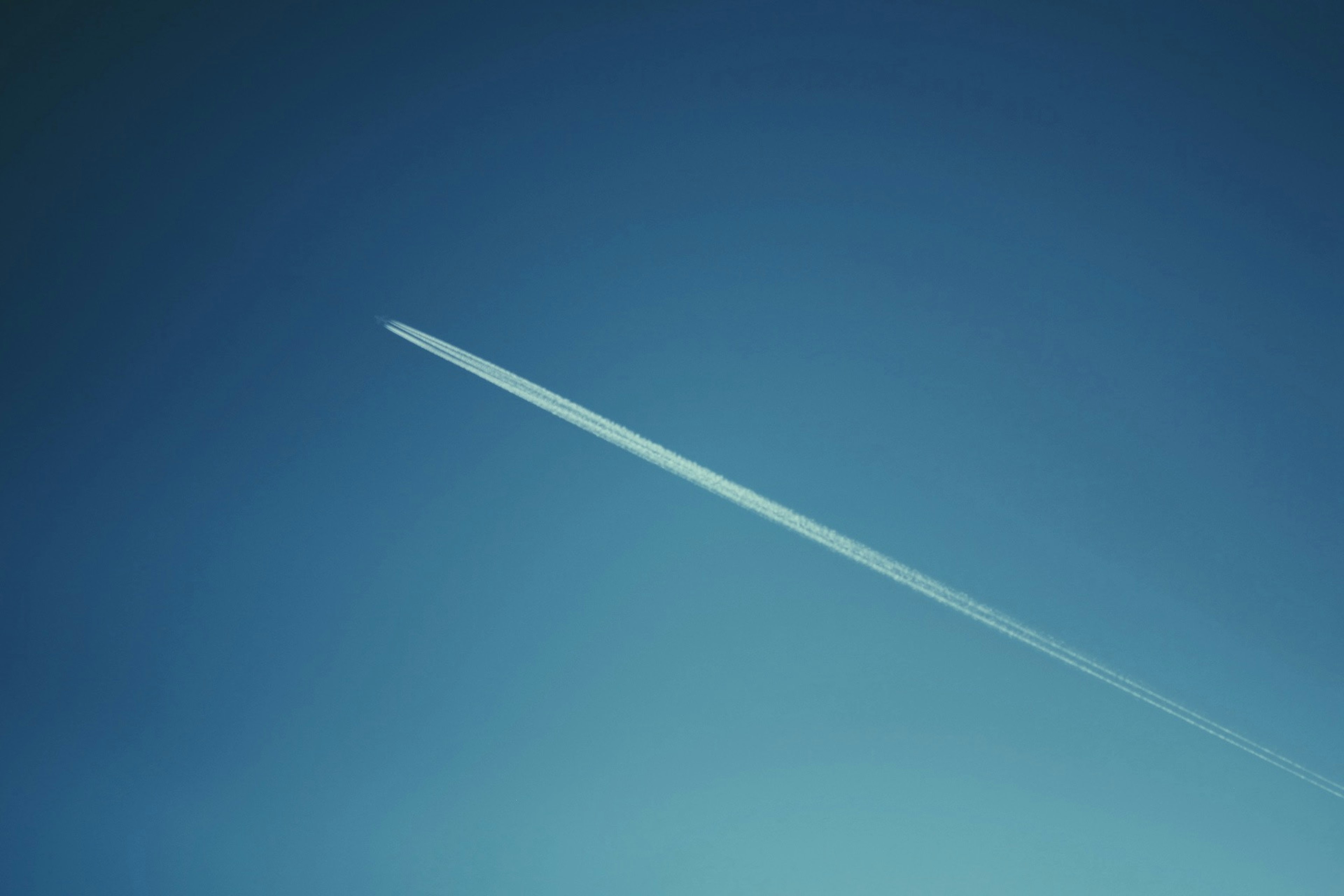 青い空に飛行機雲が伸びる風景