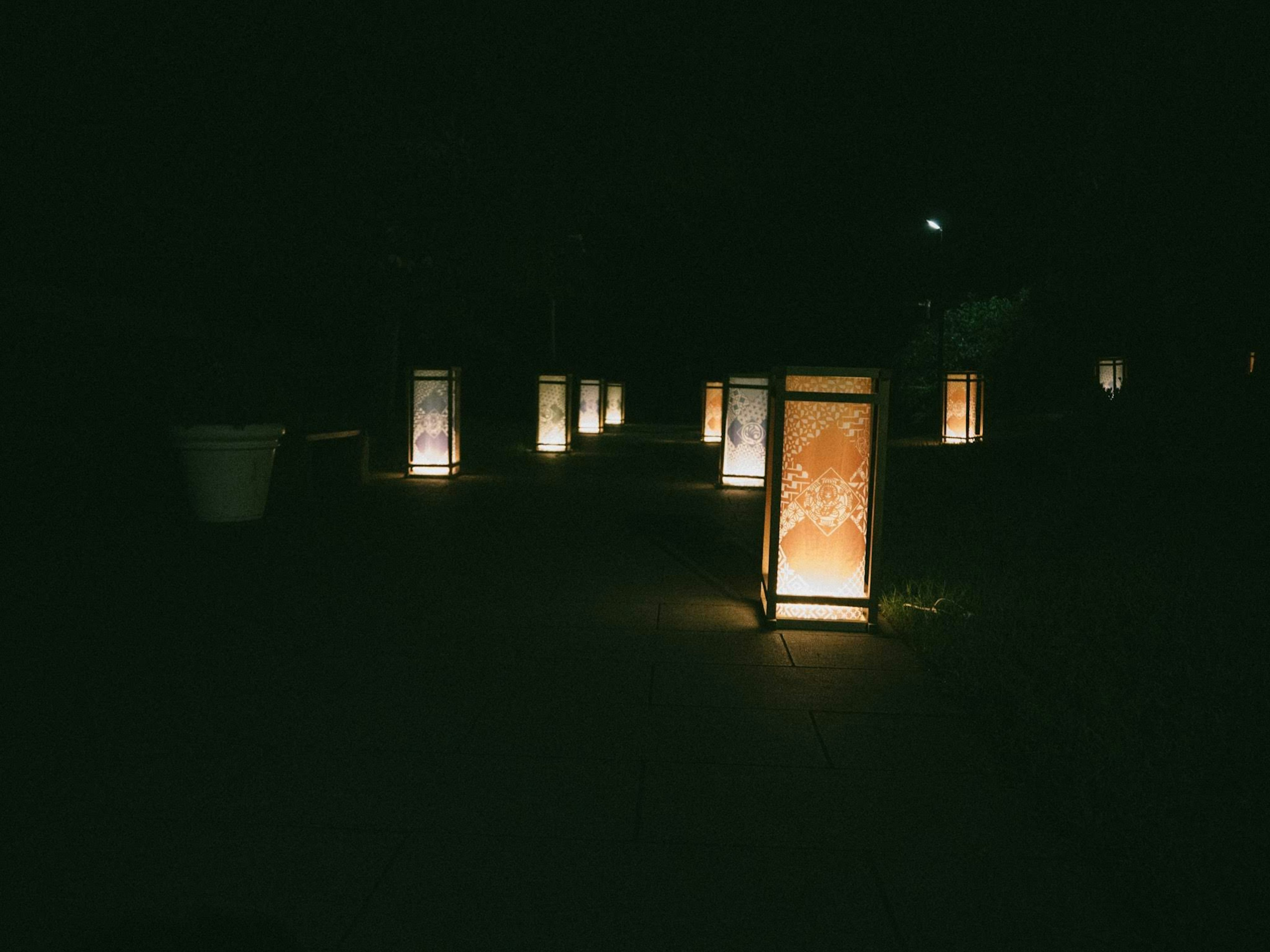 Group of illuminated lanterns along a dark pathway