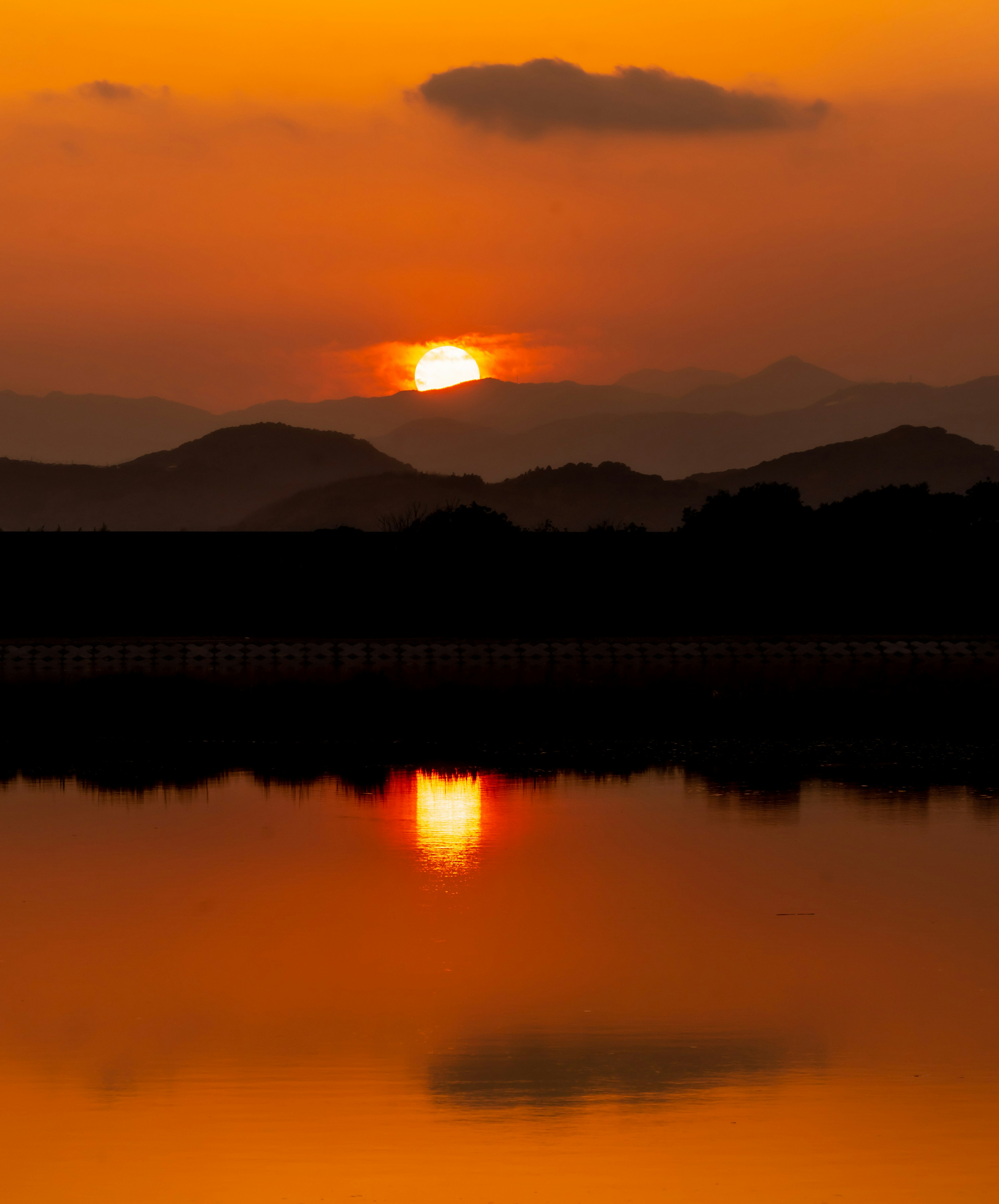 Wunderschöner Sonnenuntergang über den Bergen mit Reflexion im ruhigen Wasser