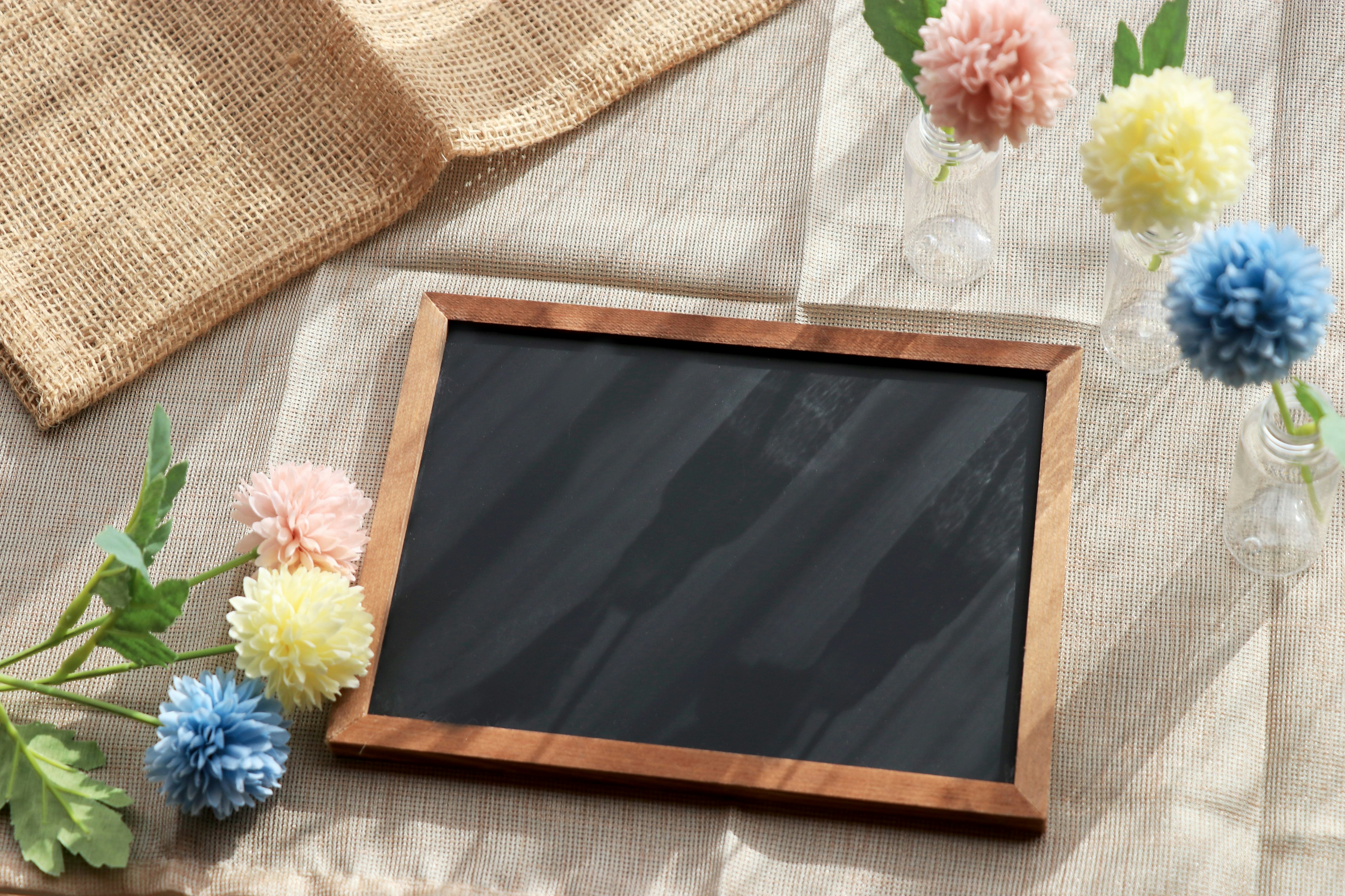 A wooden-framed chalkboard surrounded by colorful flowers in a serene setting