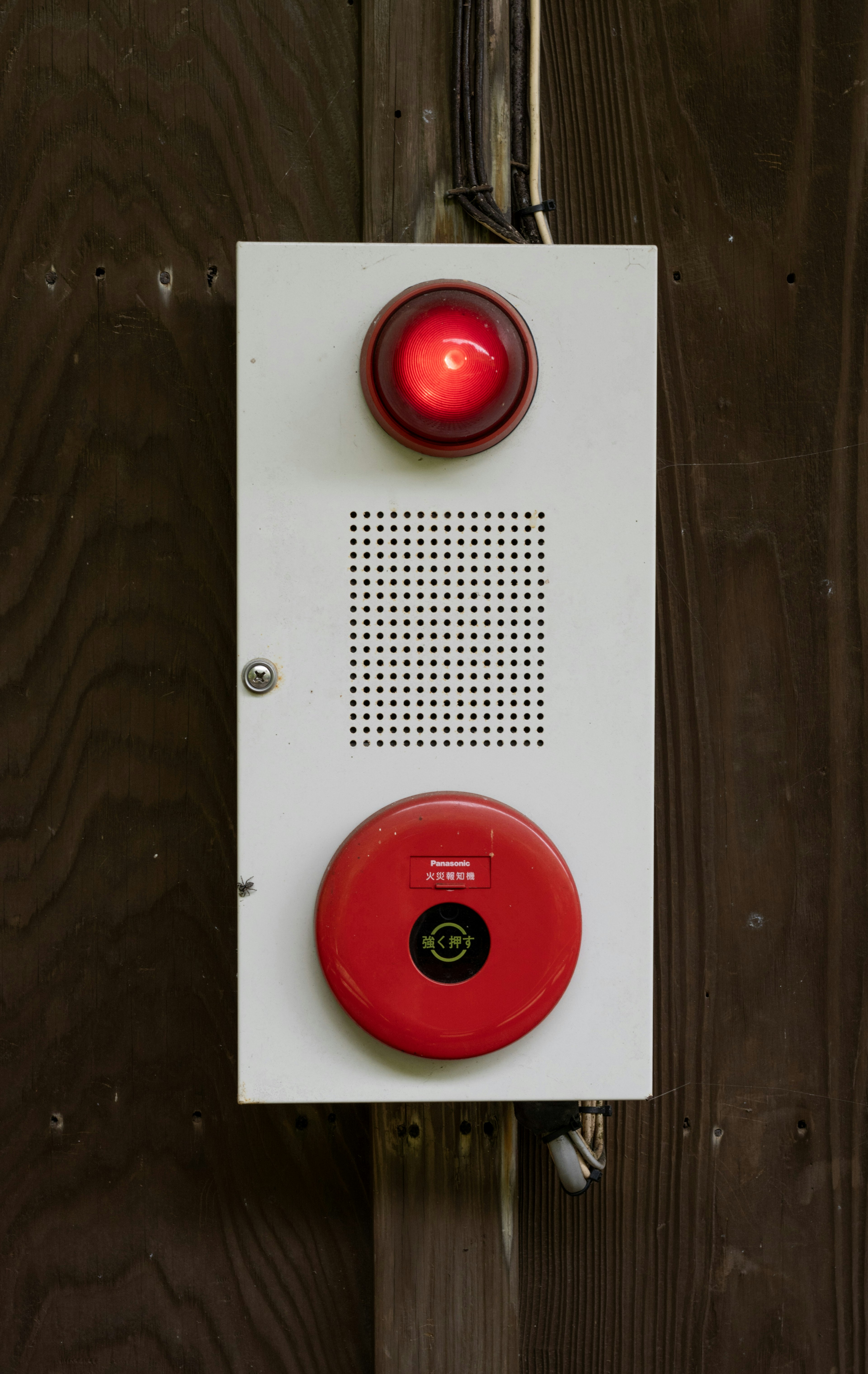 White alarm panel featuring a red warning light and red button