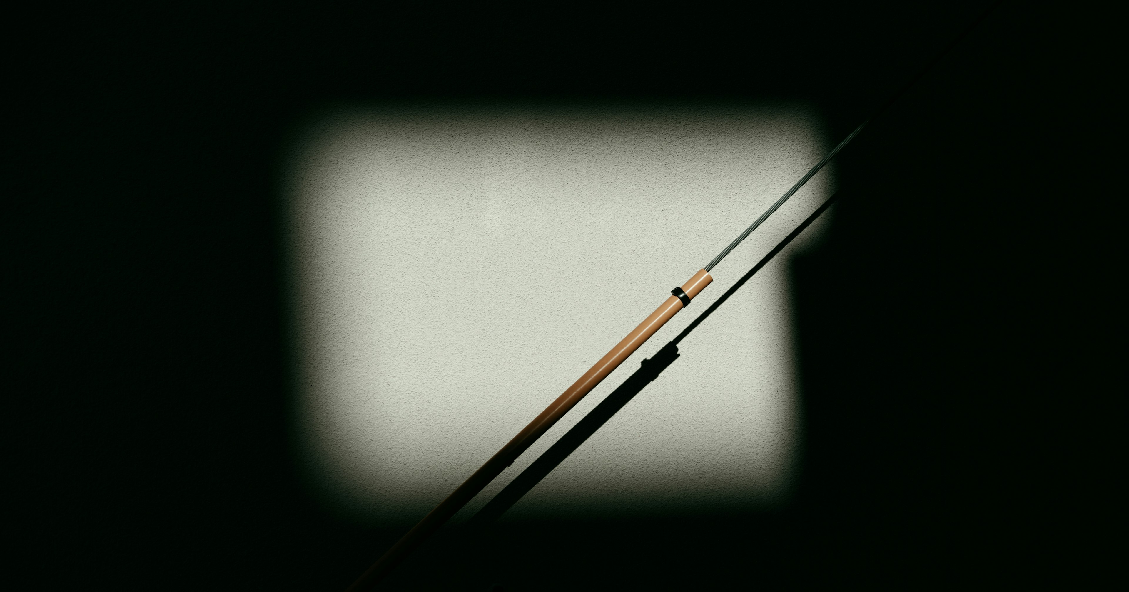 Silhouette of two fishing rods crossing against a dark background