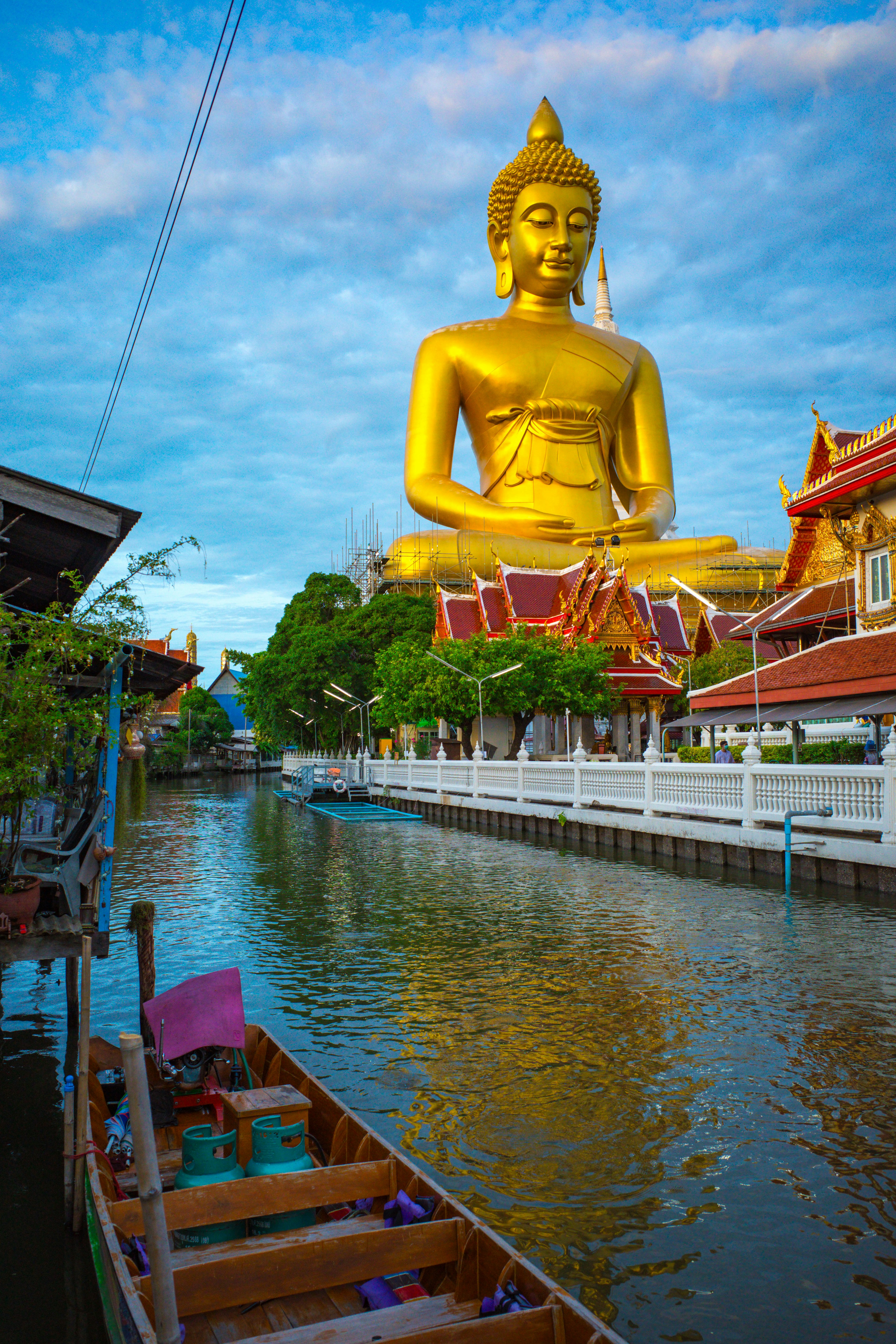 Patung Buddha besar berwarna emas mengawasi saluran yang tenang