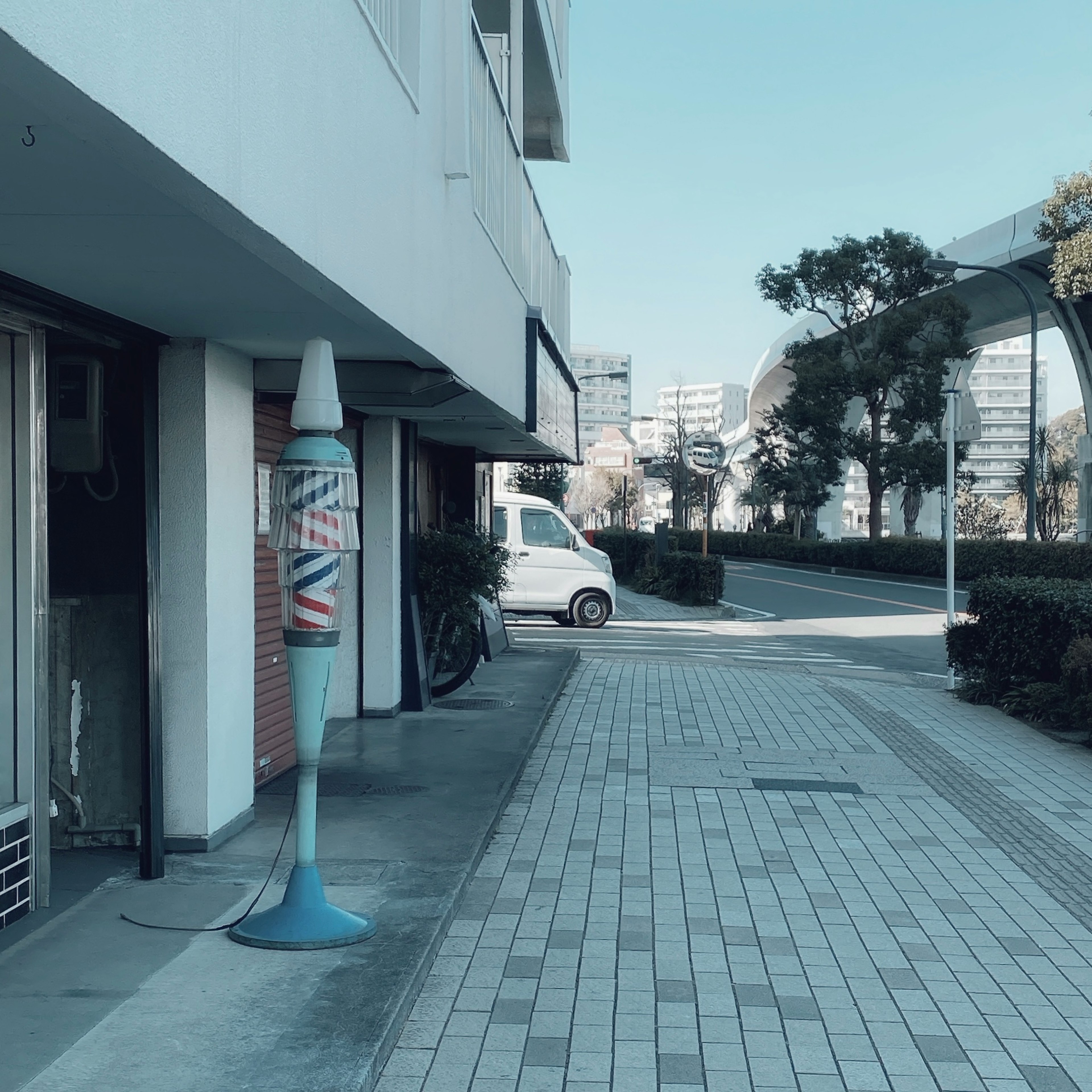 青いペンの形をした看板が立っている歩道の風景