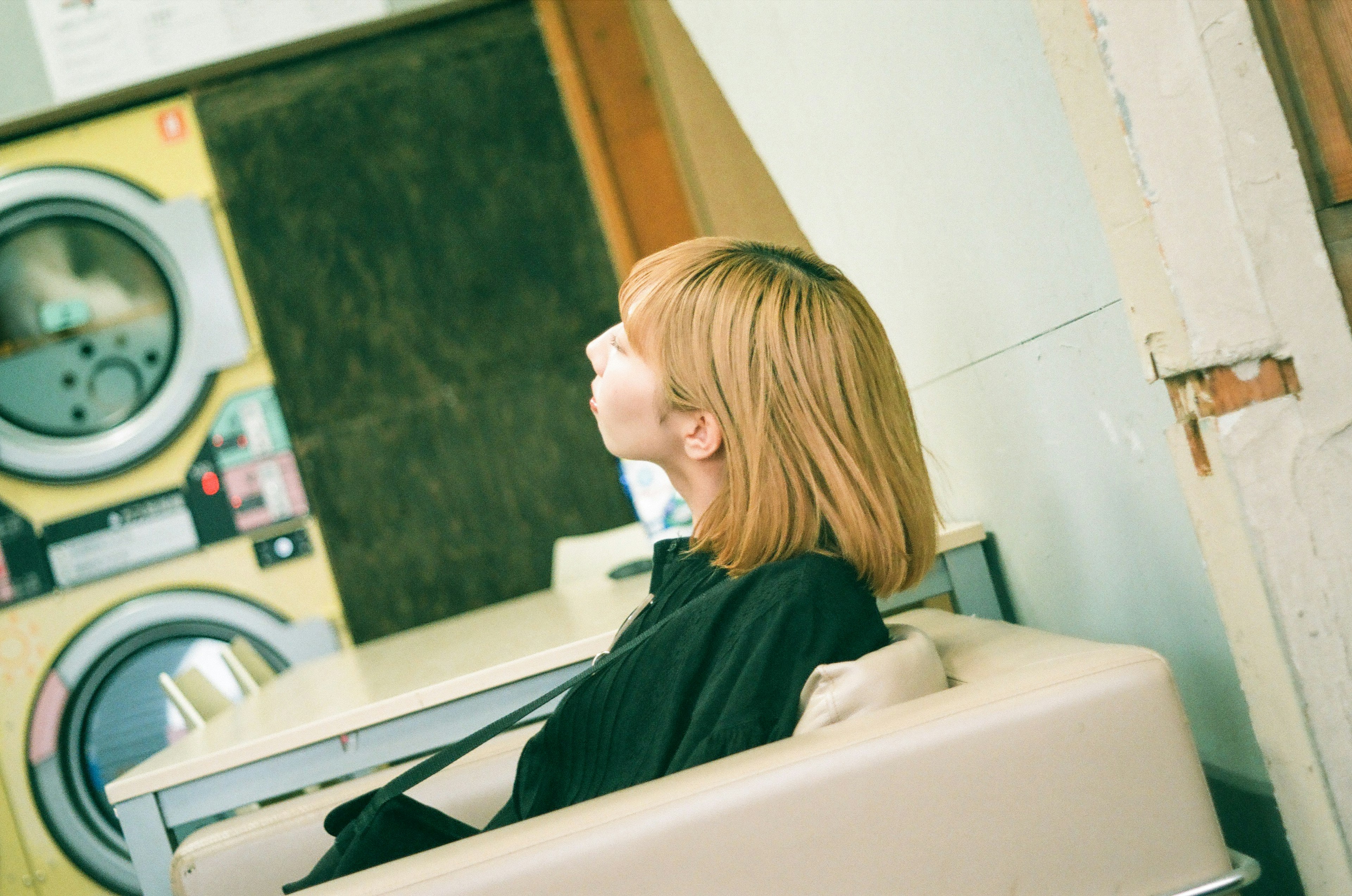 A woman relaxing near a washing machine in a laundromat