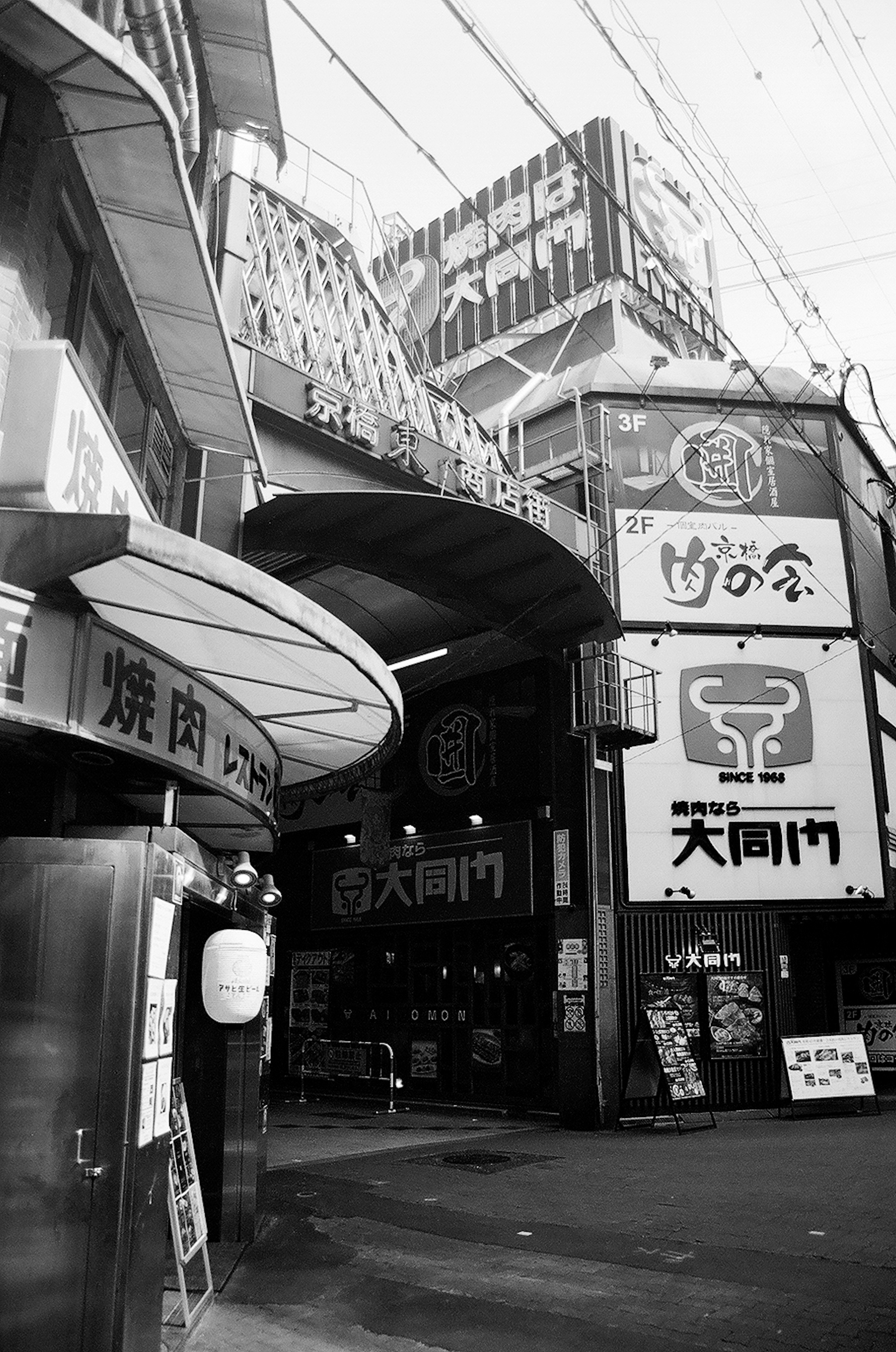 Entrada de una zona comercial con varios letreros en blanco y negro