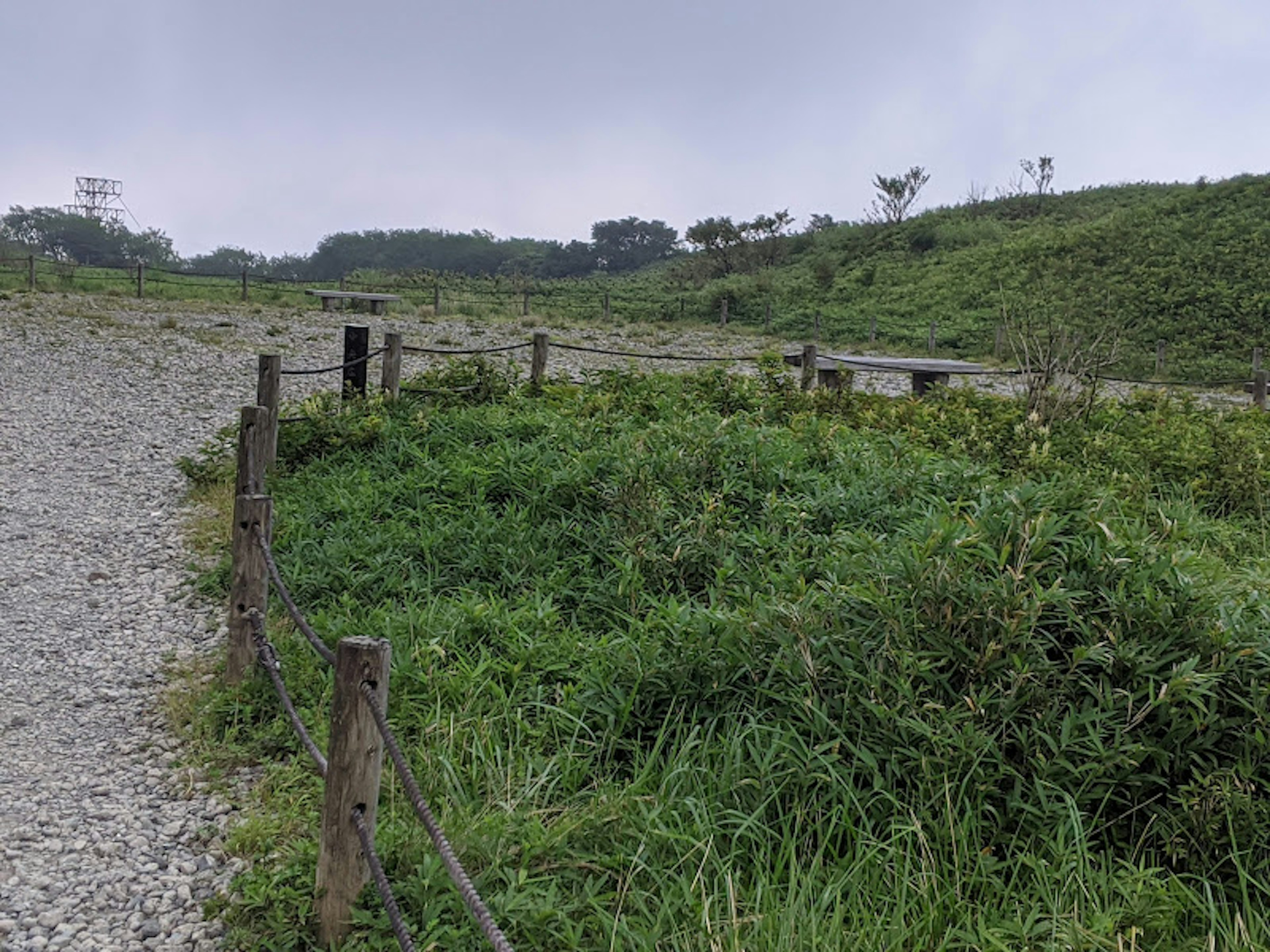 緑の草地と小石の道が見える風景、木製のフェンスが周囲を囲んでいる