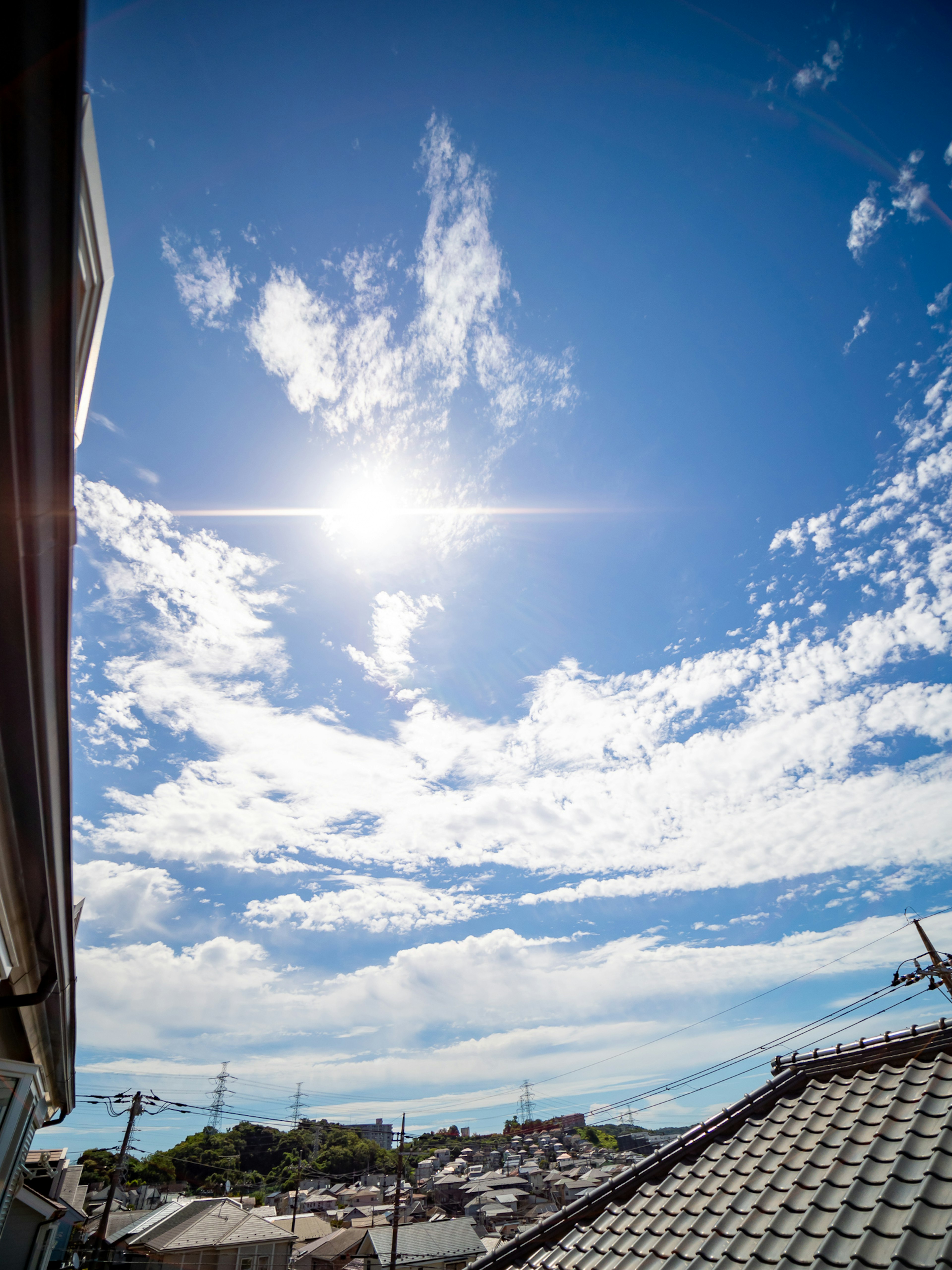 Heller blauer Himmel mit weißen Wolken Sonnenlicht scheint über die Dächer