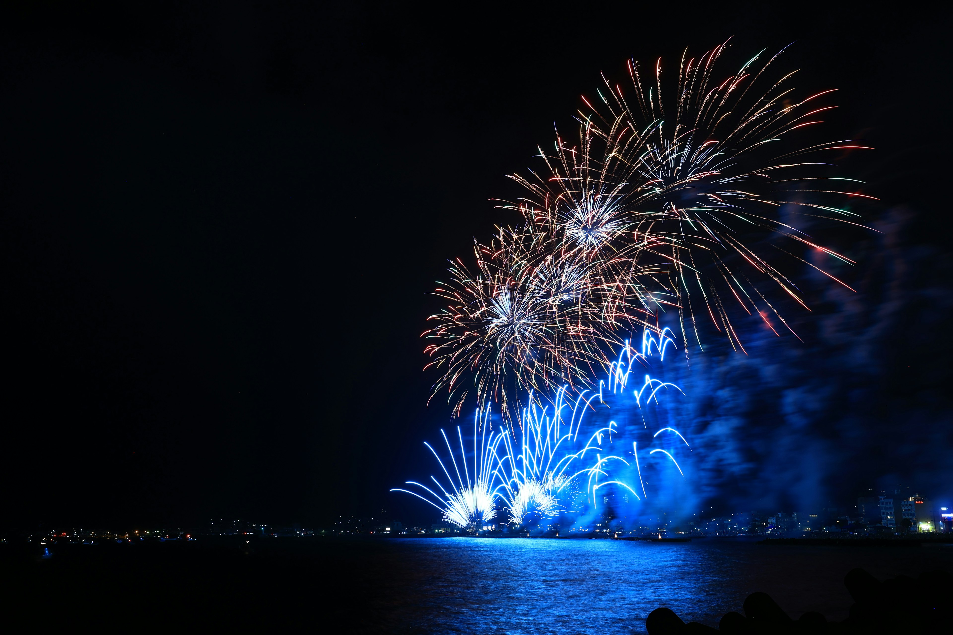 Fuochi d'artificio vibranti illuminano il cielo notturno con scoppi di colori blu e bianchi