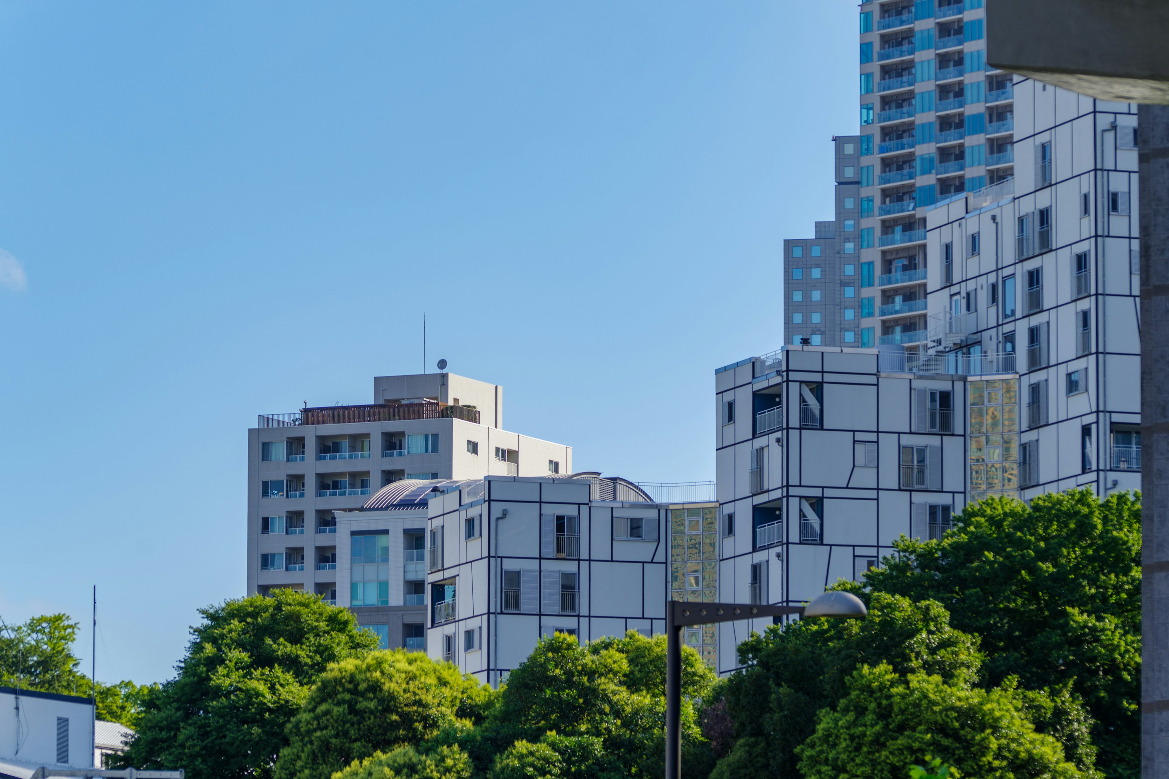 Modern buildings under a clear blue sky with green trees