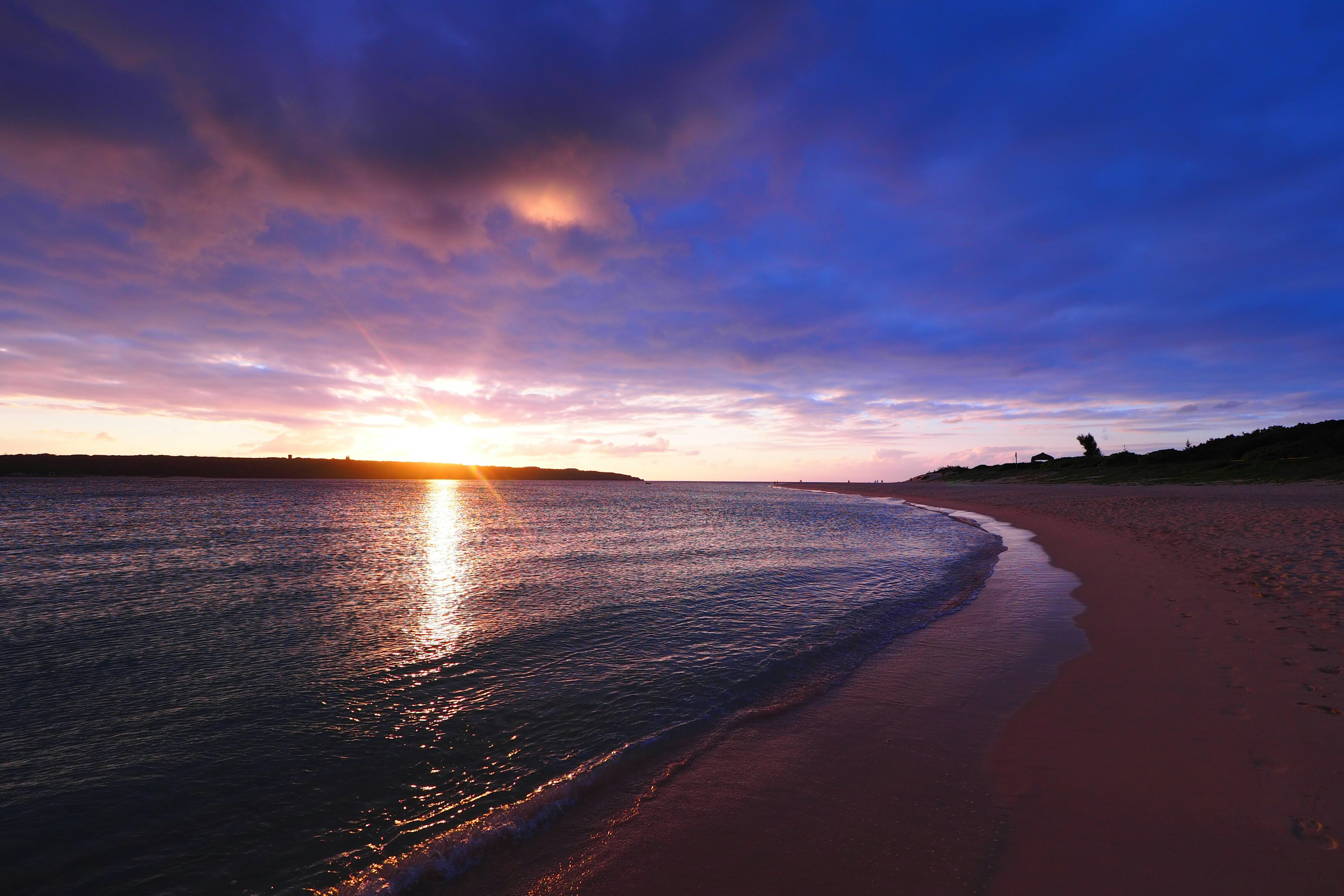 Wunderschöner Sonnenuntergang über einem ruhigen Strand mit sanften Wellen