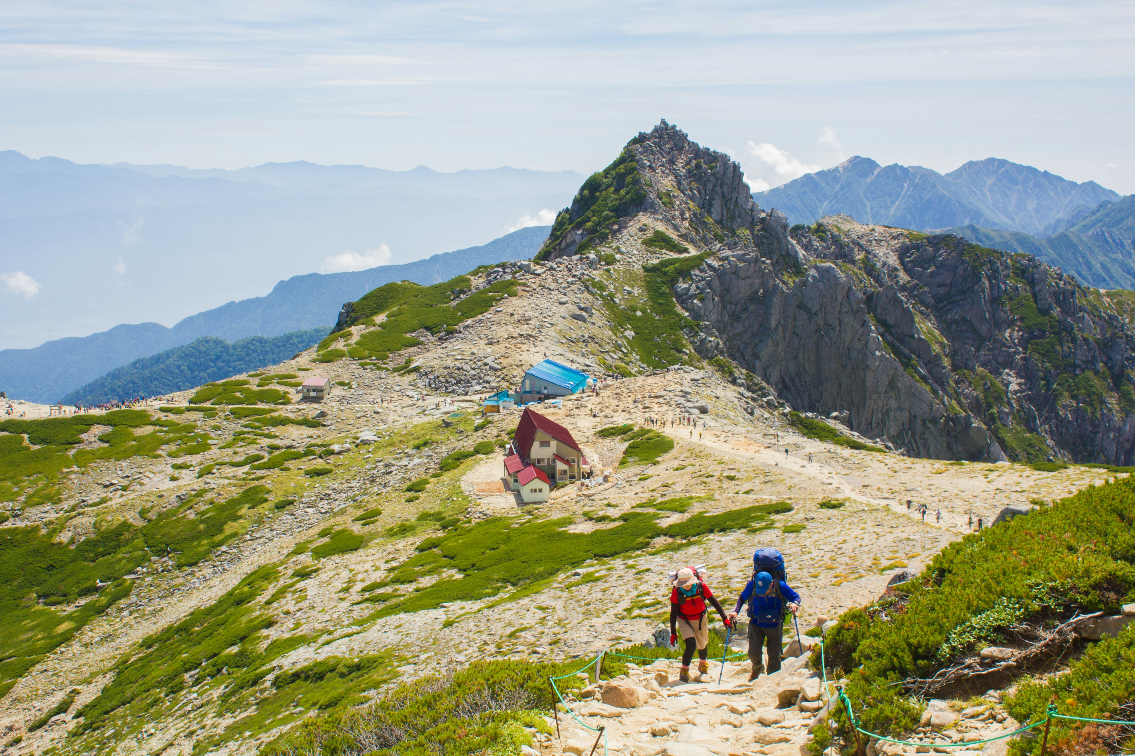 Deux randonneurs marchant sur un sentier de montagne avec un paysage magnifique