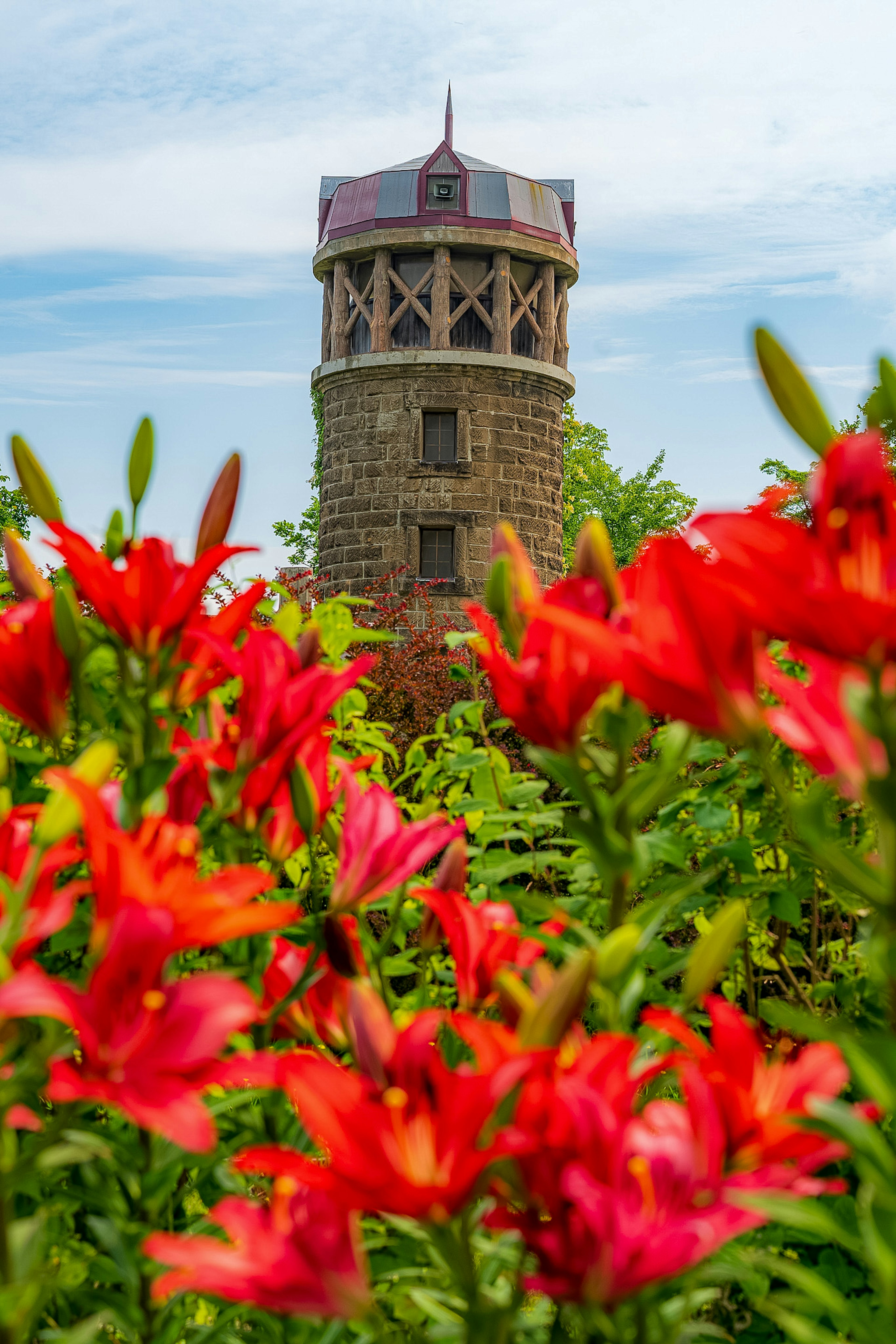 Malersicher Blick auf einen Steinturm umgeben von roten Blumen