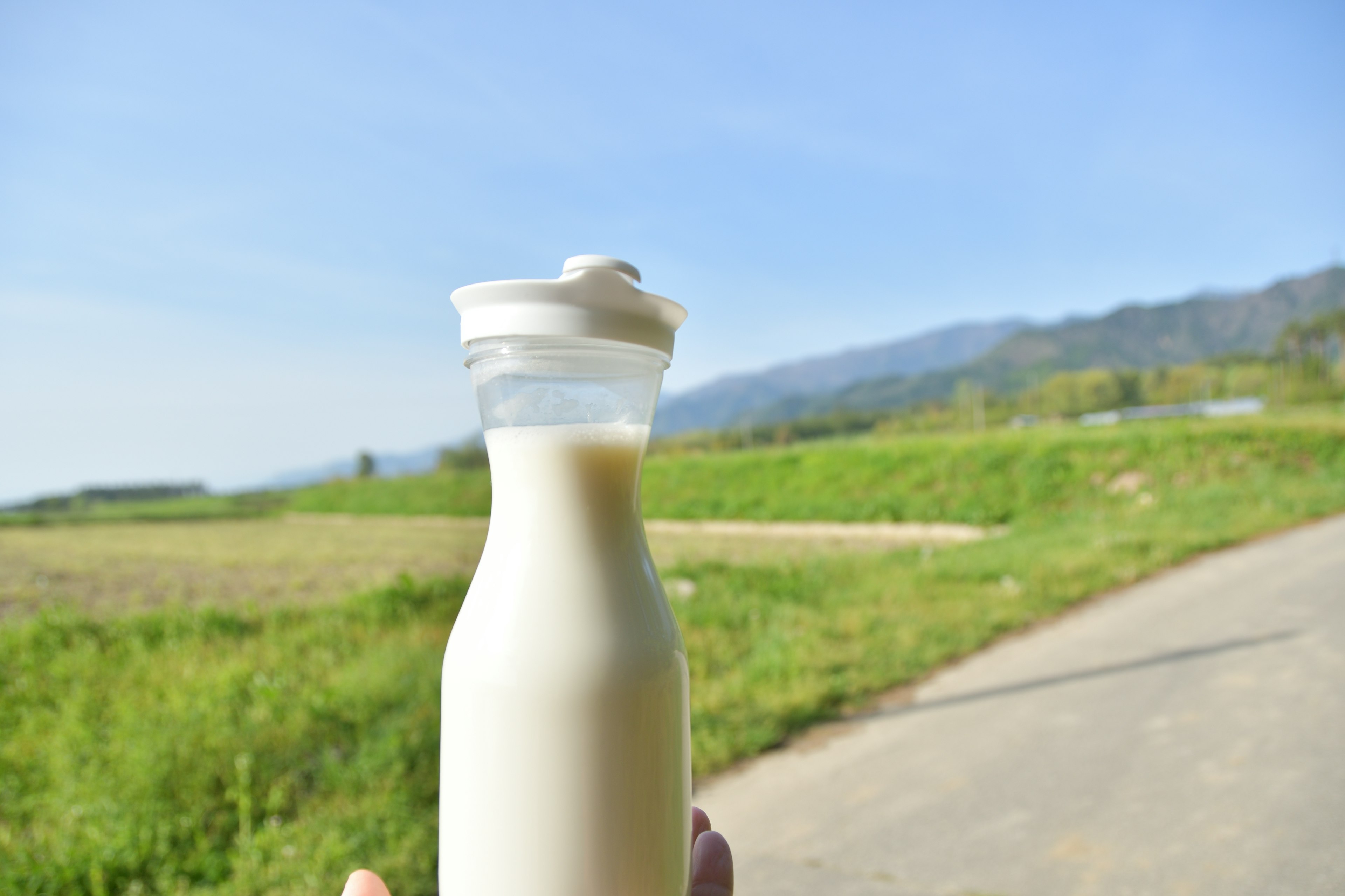 Glasflasche mit frischer Milch vor blauem Himmel