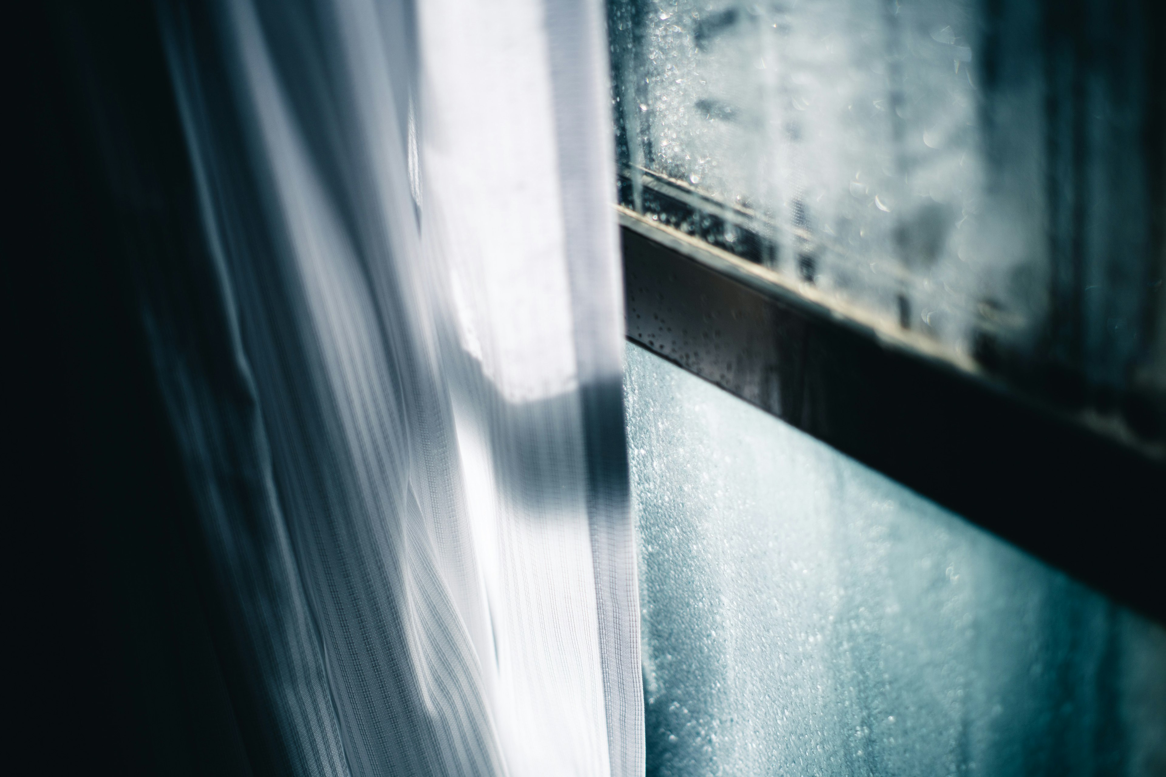 Close-up shot of a window with water droplets and a curtain