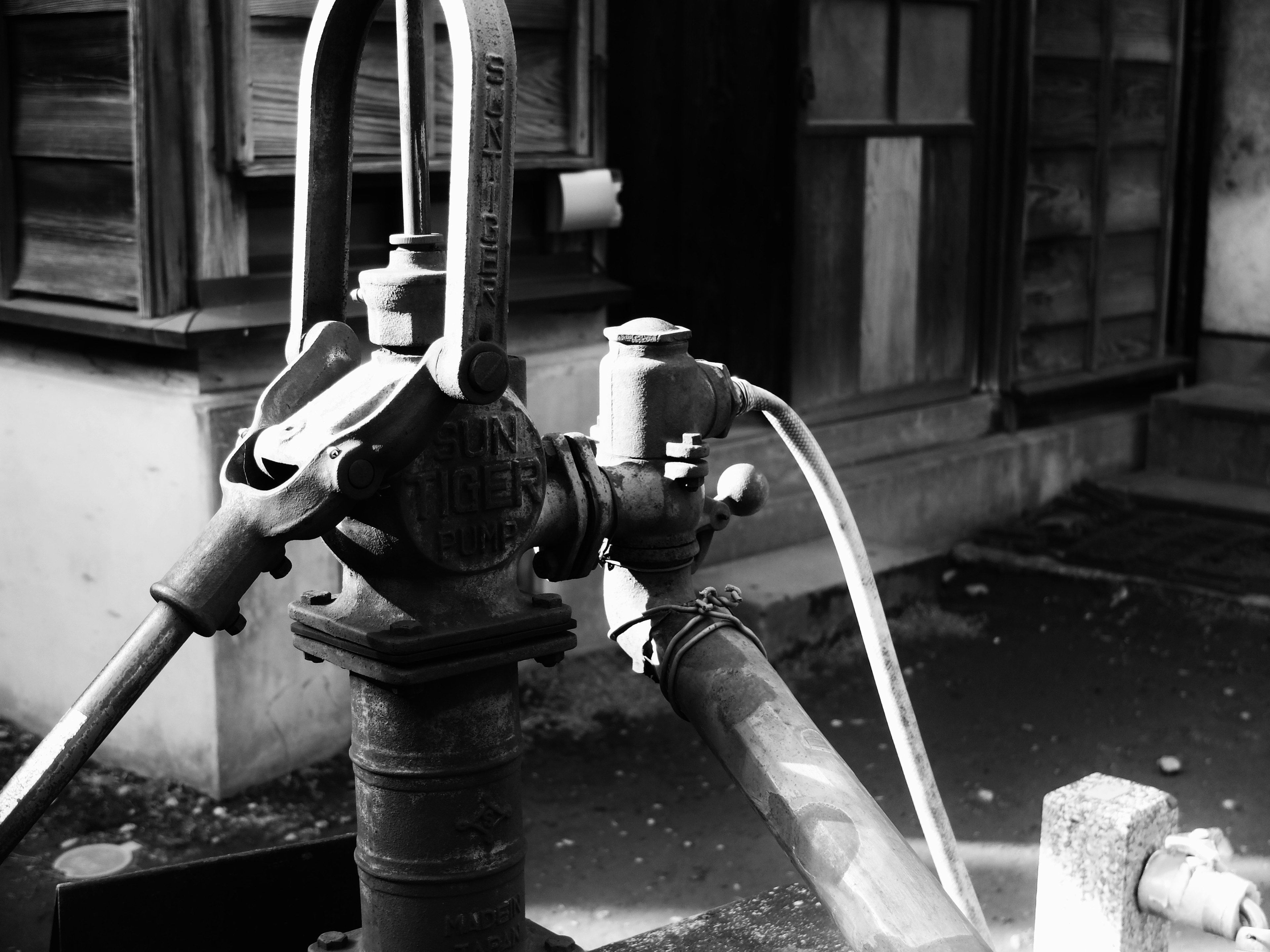 Vieja bomba de agua manual en un entorno en blanco y negro