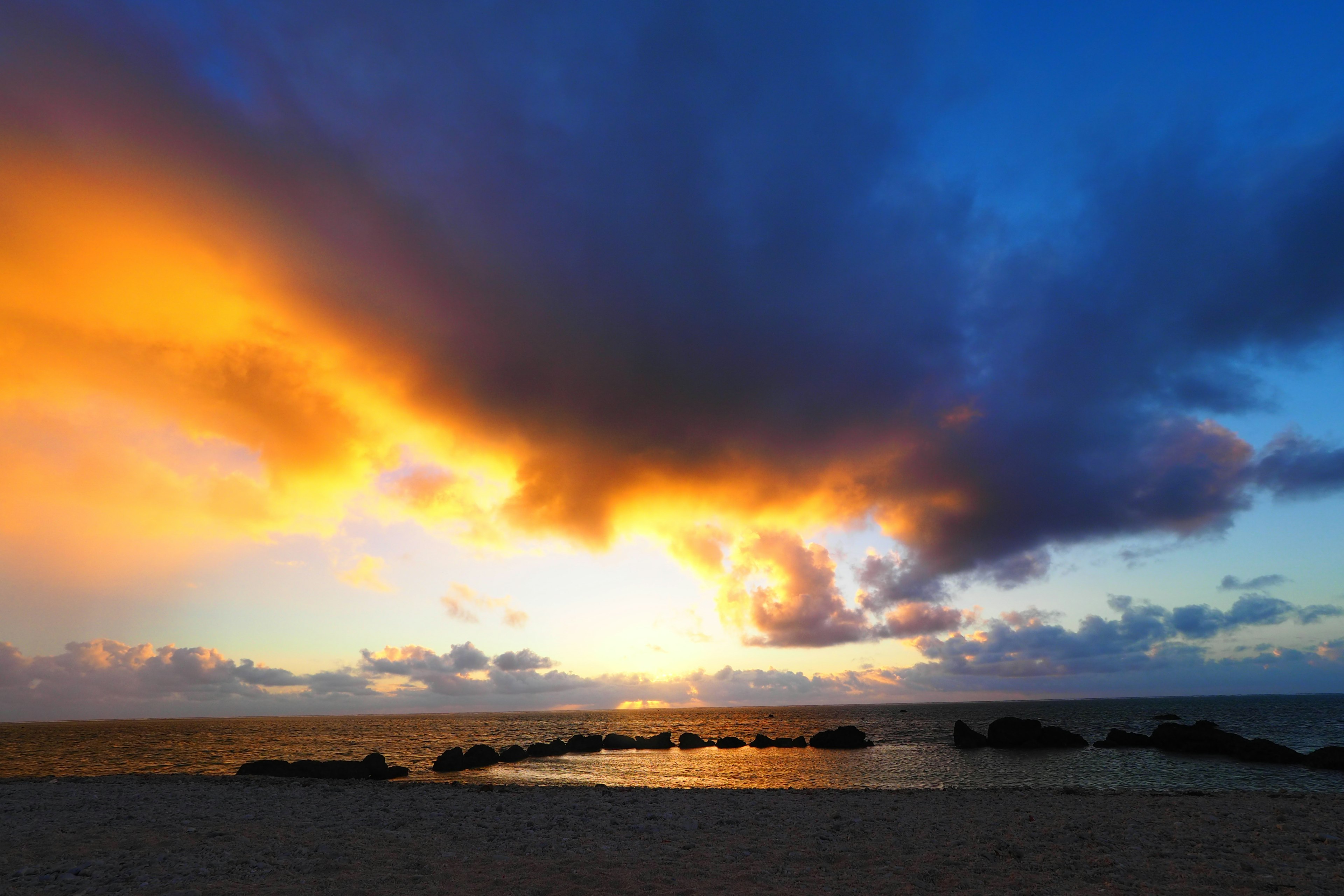 美しい夕焼けが広がる海の風景 黒い岩が海に並ぶ