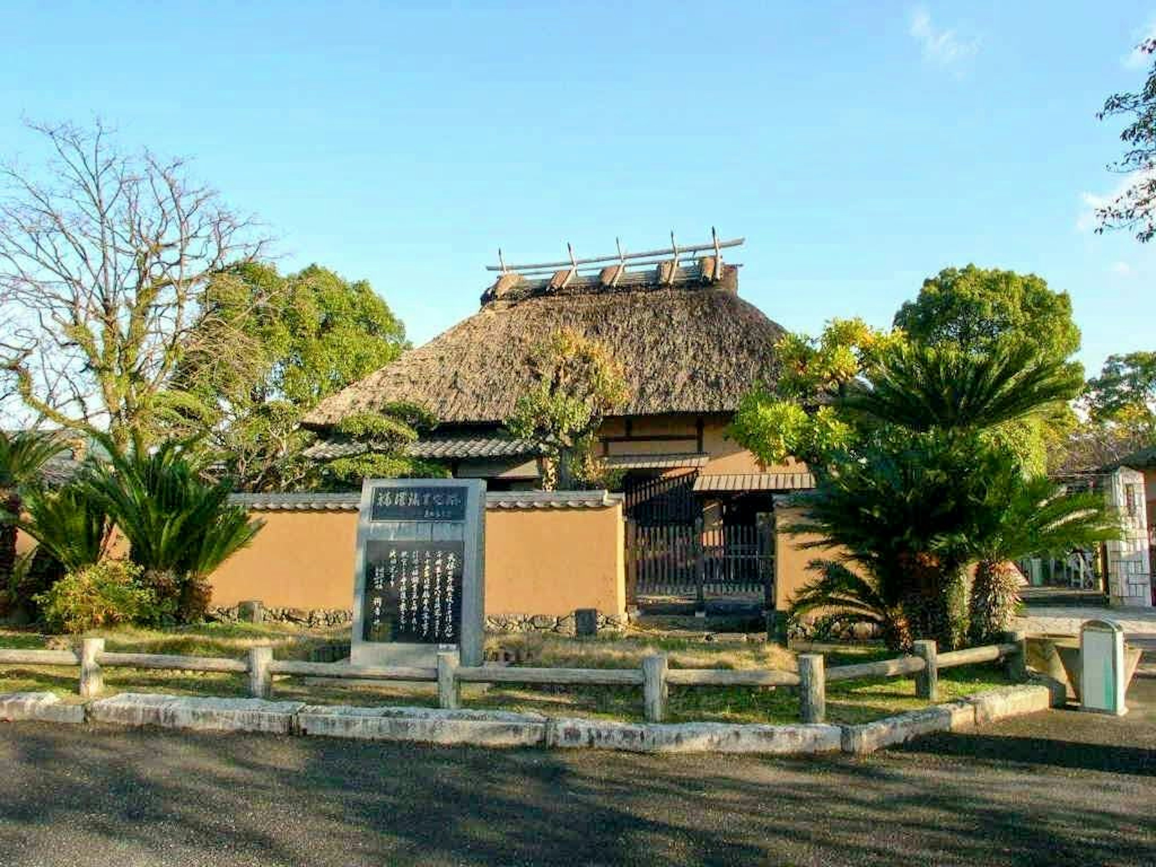 Maison japonaise traditionnelle avec toit de chaume et verdure environnante