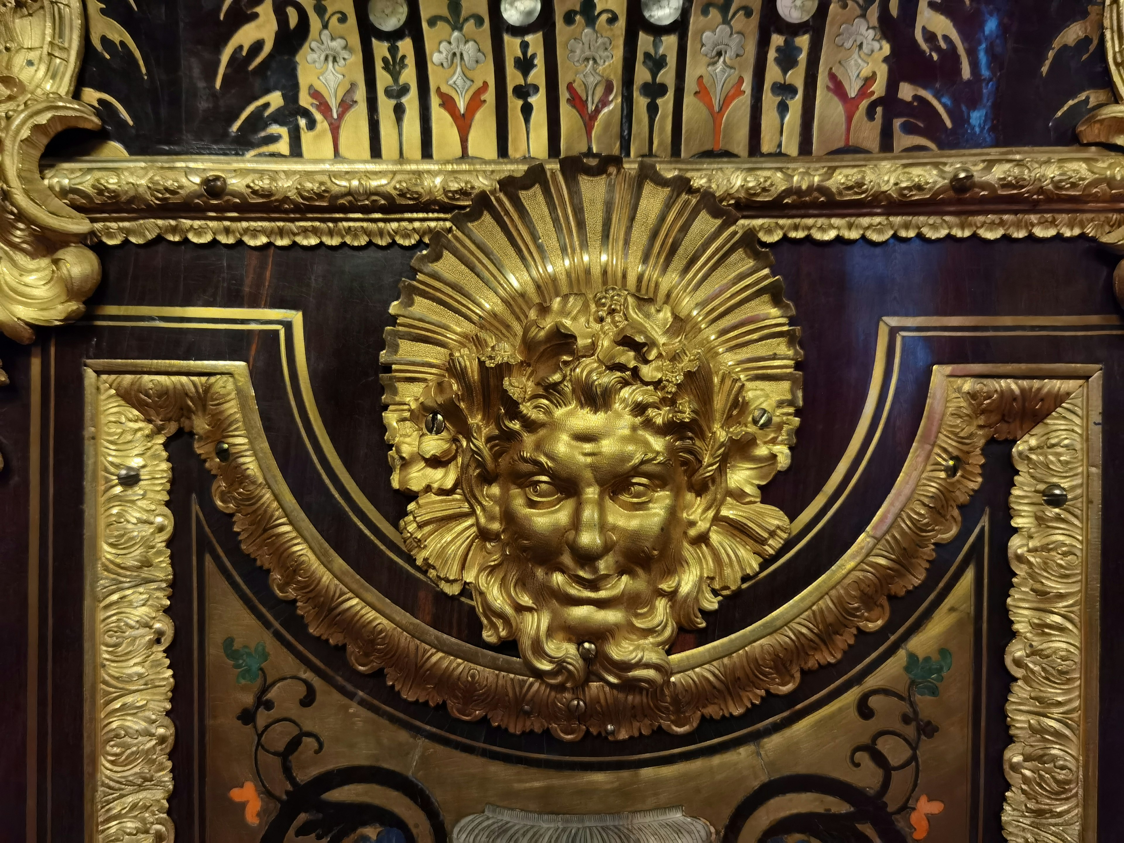 Un elemento decorativo de pared con una escultura dorada del rostro de un dios del sol