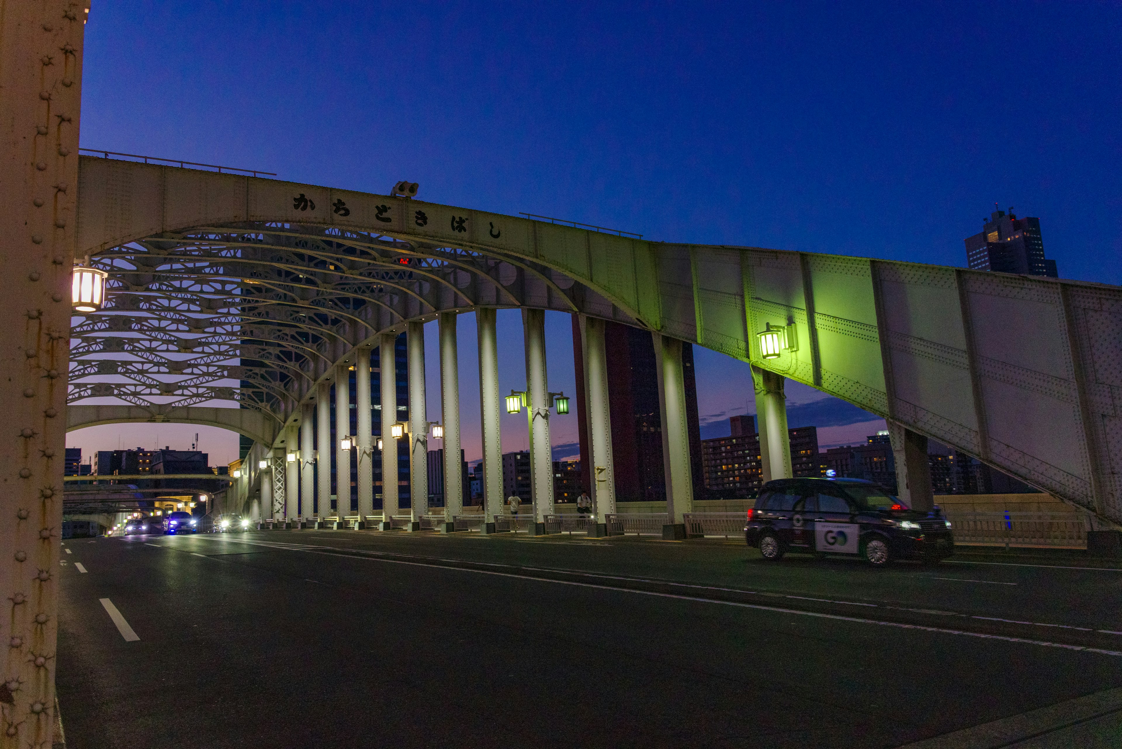 Ponte ad arco illuminato al crepuscolo con auto che passano sotto