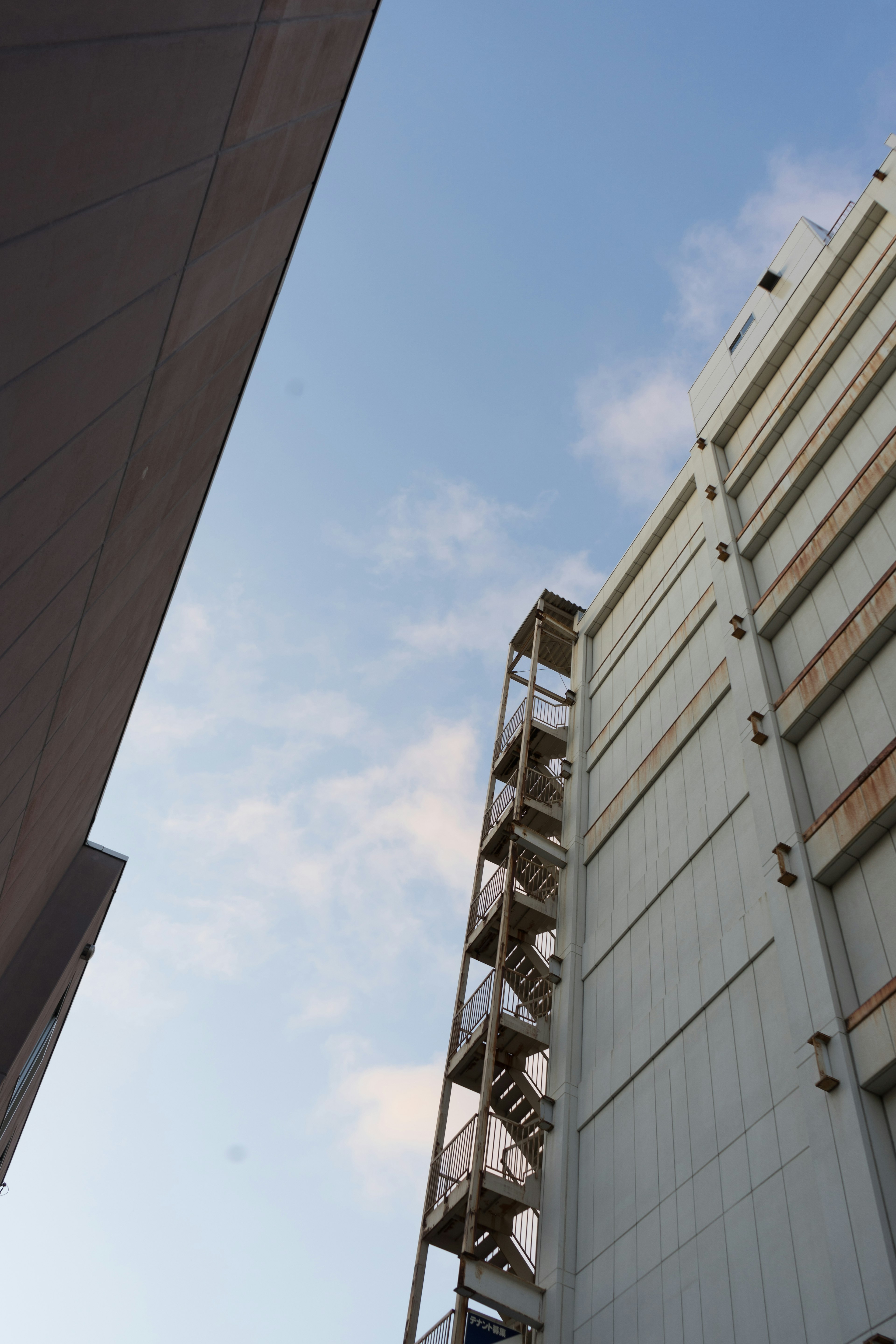 View looking up at a building with stairs against a blue sky