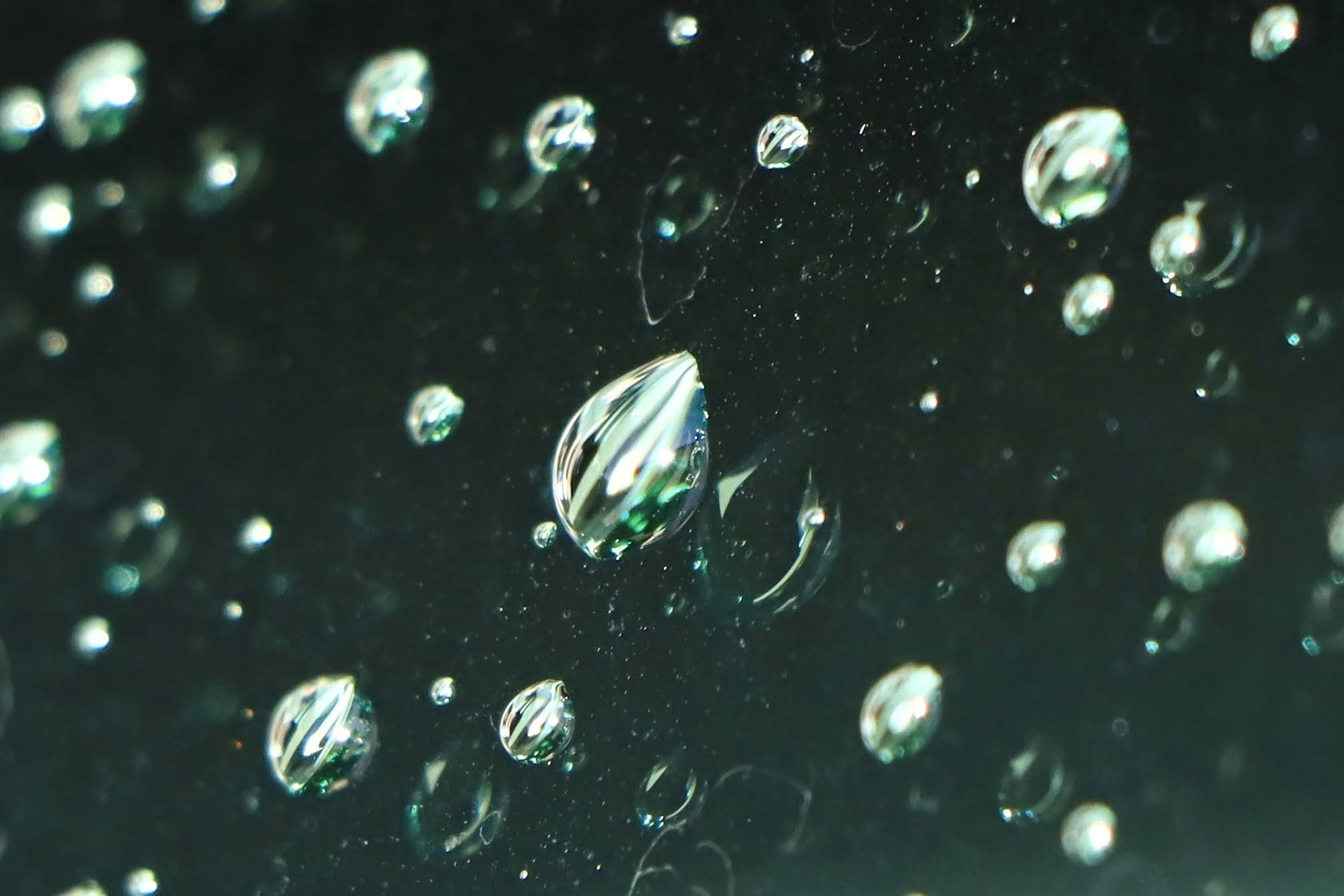 Water droplets on a dark background with varied sizes and reflections