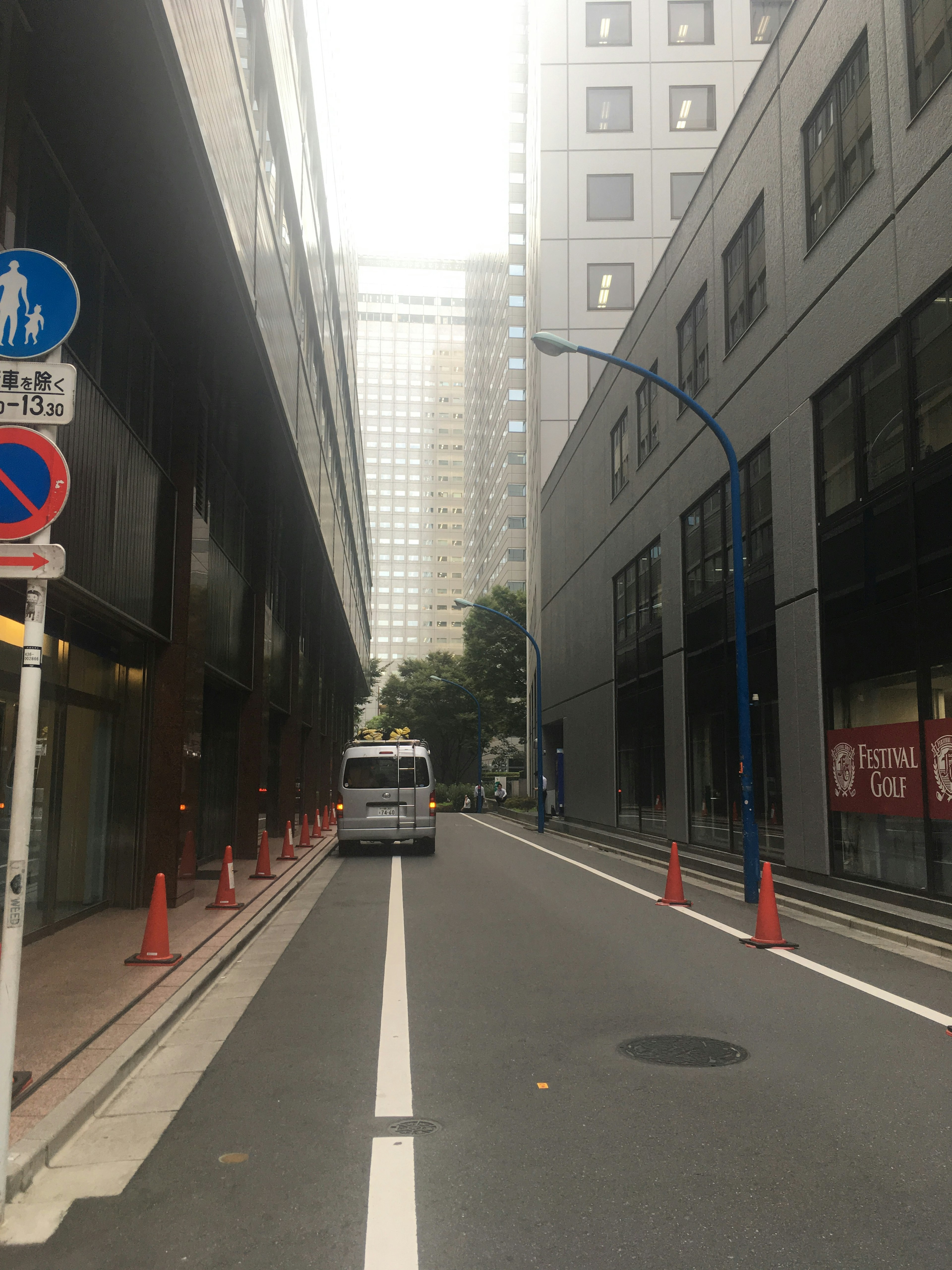 狭い道に沿った両側のビルとパーキングの表示がある都市の風景