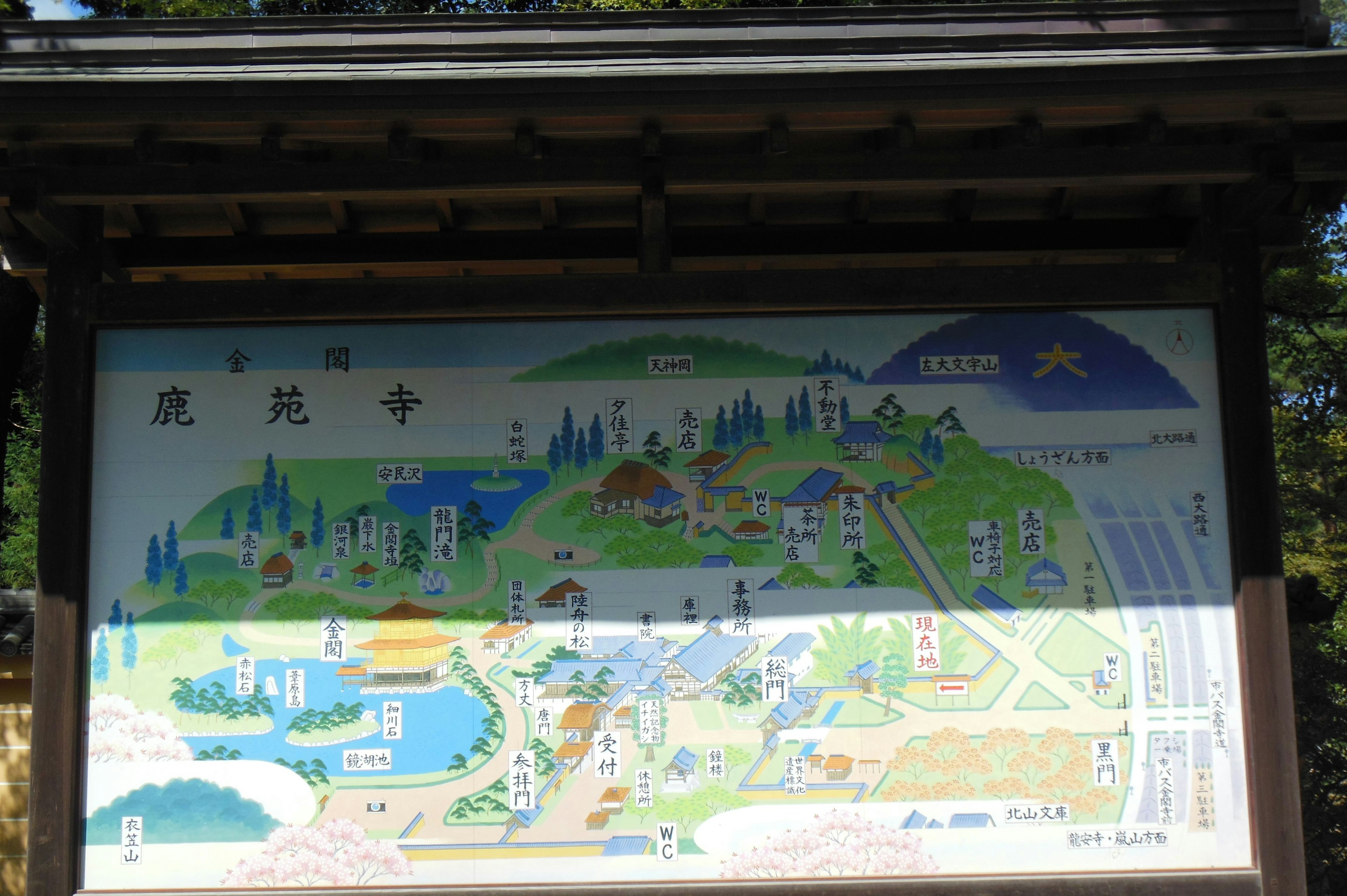 A colorful illustrated map sign depicting a scenic landscape with various buildings and natural elements