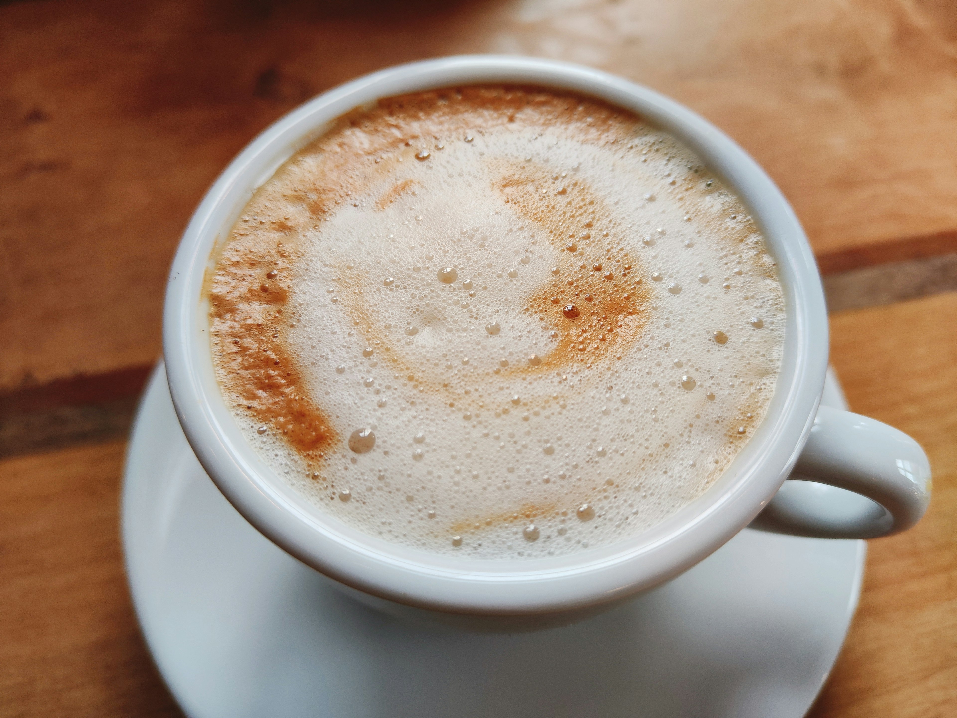 A creamy coffee in a white cup with beautiful frothy patterns on top