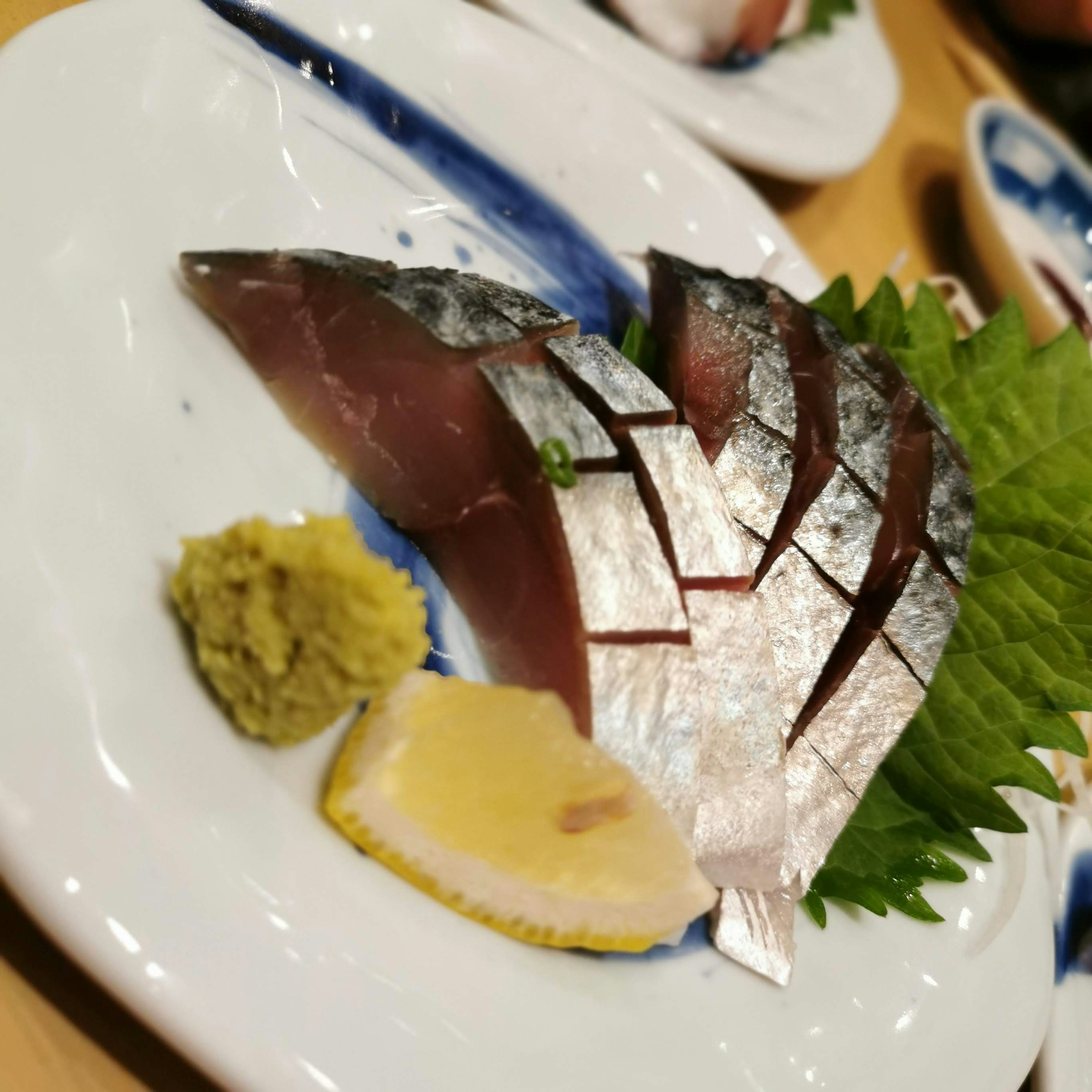 Sashimi segar dengan wasabi dan lemon di atas piring putih